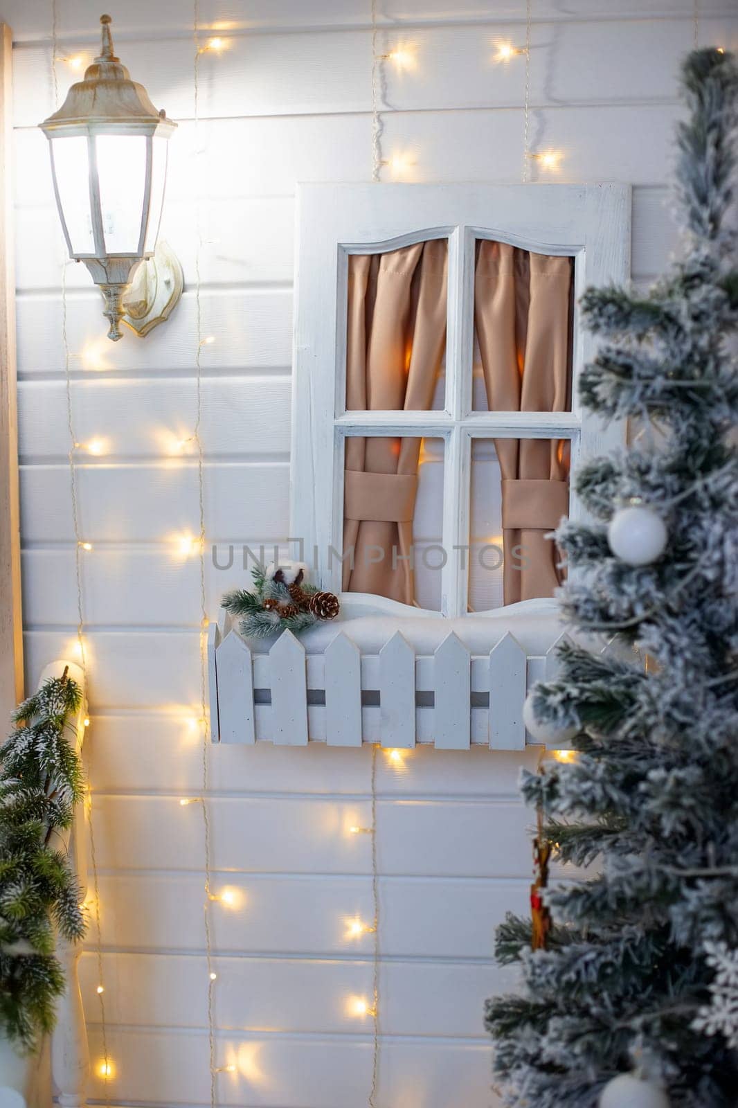 White wall with New Year's decorations : spruce, white window toy and lantern. Vertical