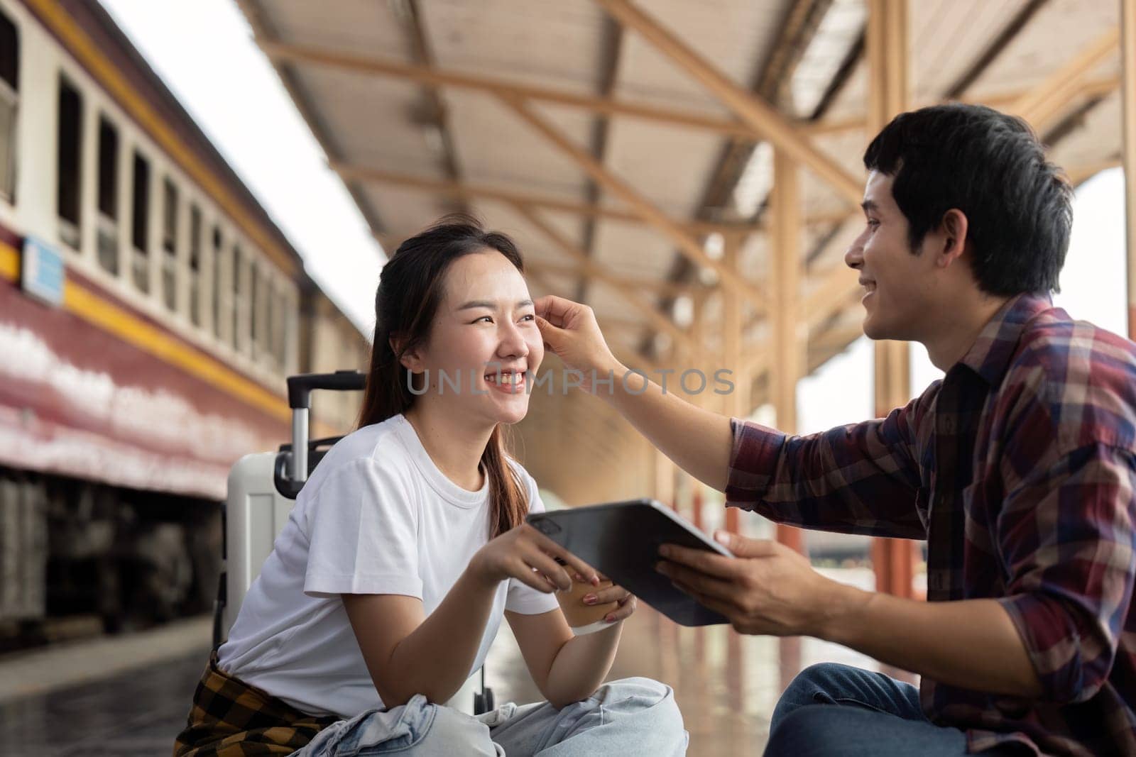 While waiting for their train, a couple engages in playful interaction, strengthening their bond through shared travel experiences.