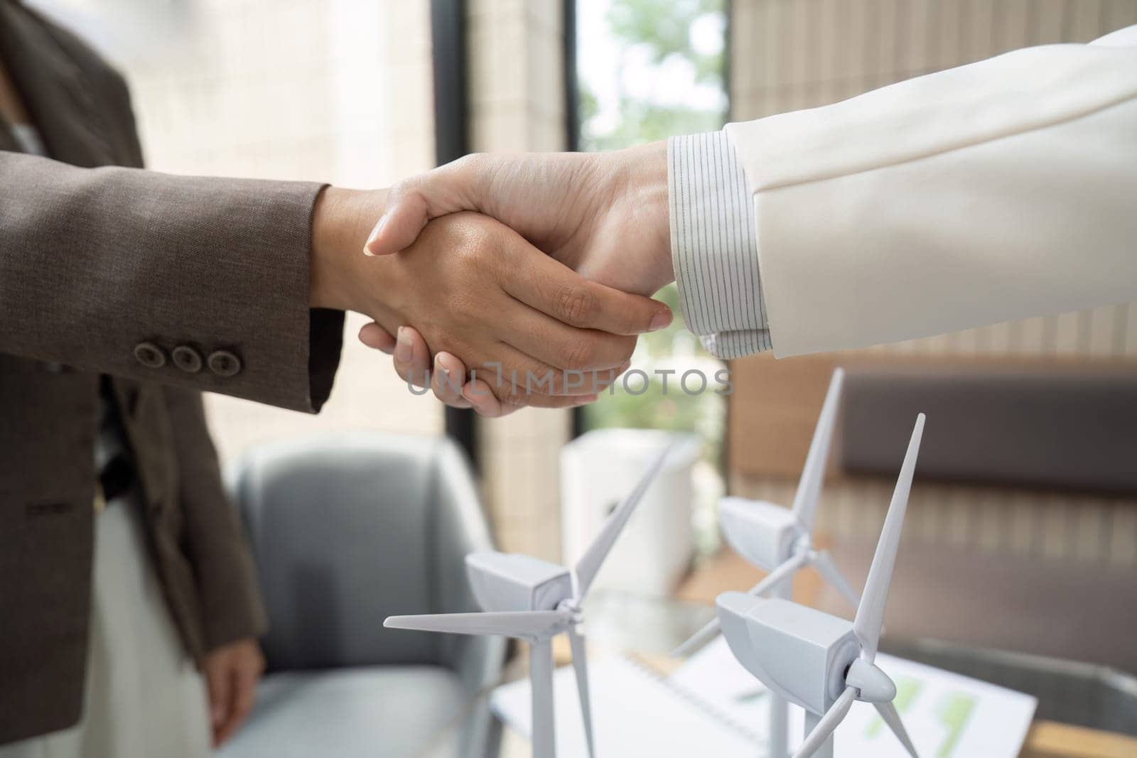 Two business partners engage in a handshake to solidify their commitment to sustainable projects, promoting environmental responsibility and collaboration in the workplace.