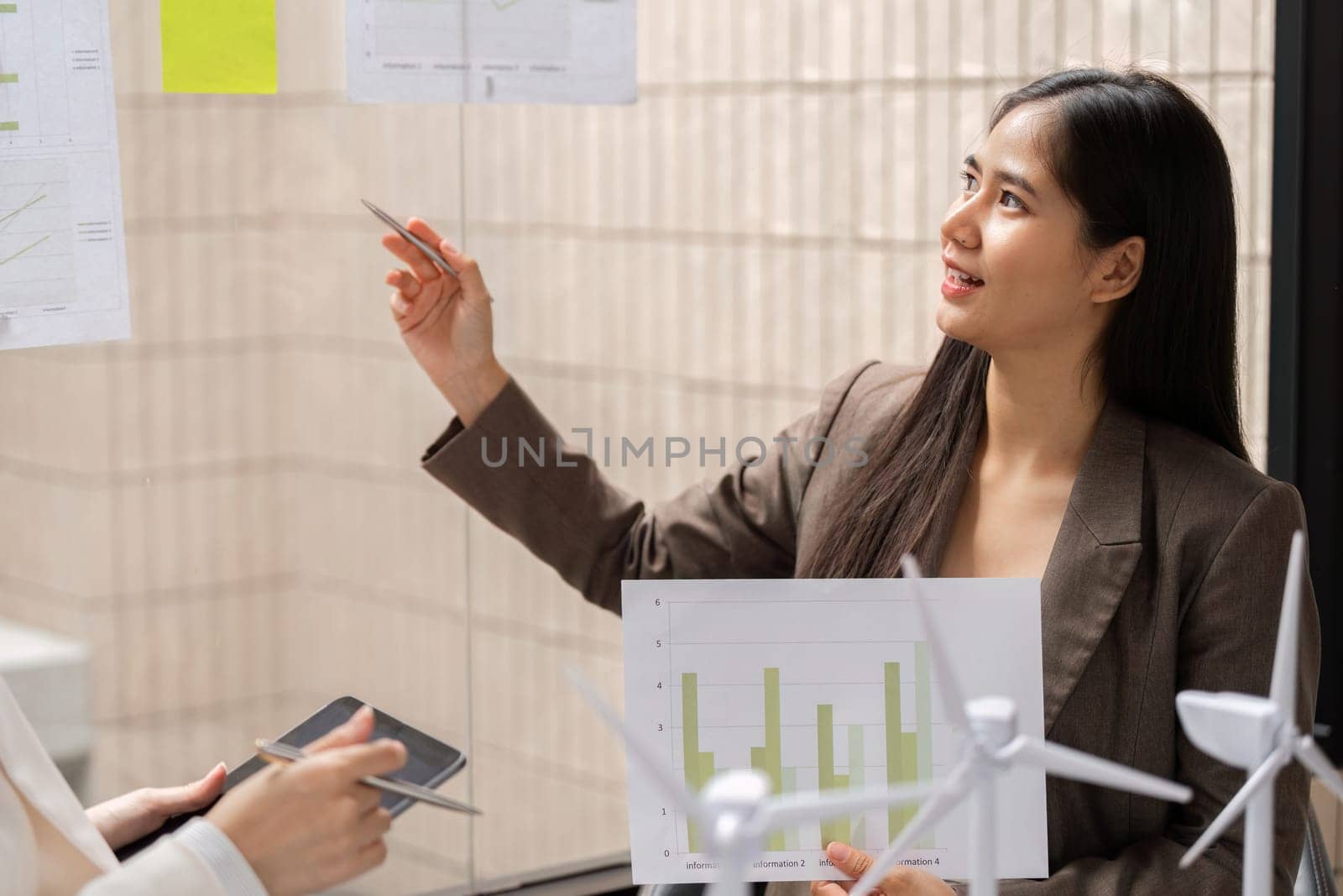 In a modern office, a woman presents sustainability data related to renewable energy, highlighting the importance of ESG metrics in decision-making.