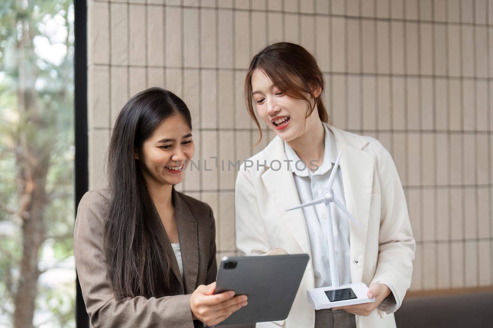 Two women engage in a discussion about renewable energy solutions, utilizing technology for better sustainable strategies.