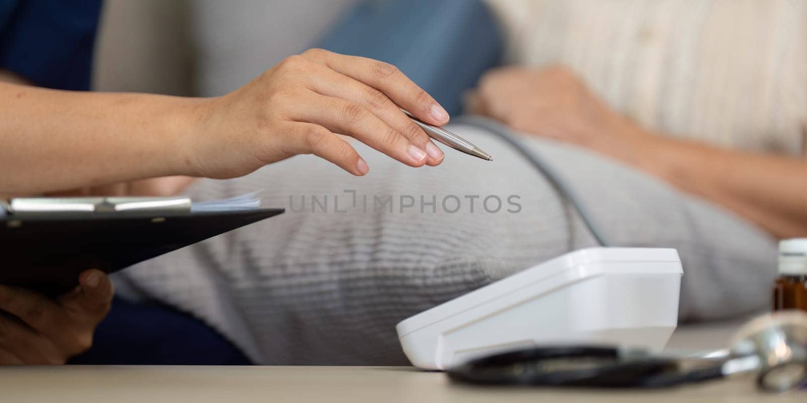 A caregiver focuses on inputting blood pressure readings, ensuring a thorough healthcare process for an elderly patient.