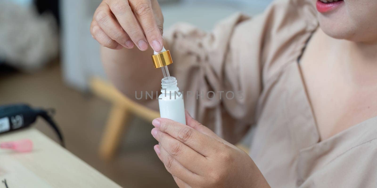 A woman prepares her skincare products by replacing the dropper lid, focusing on creating a customized experience for her beauty regimen.