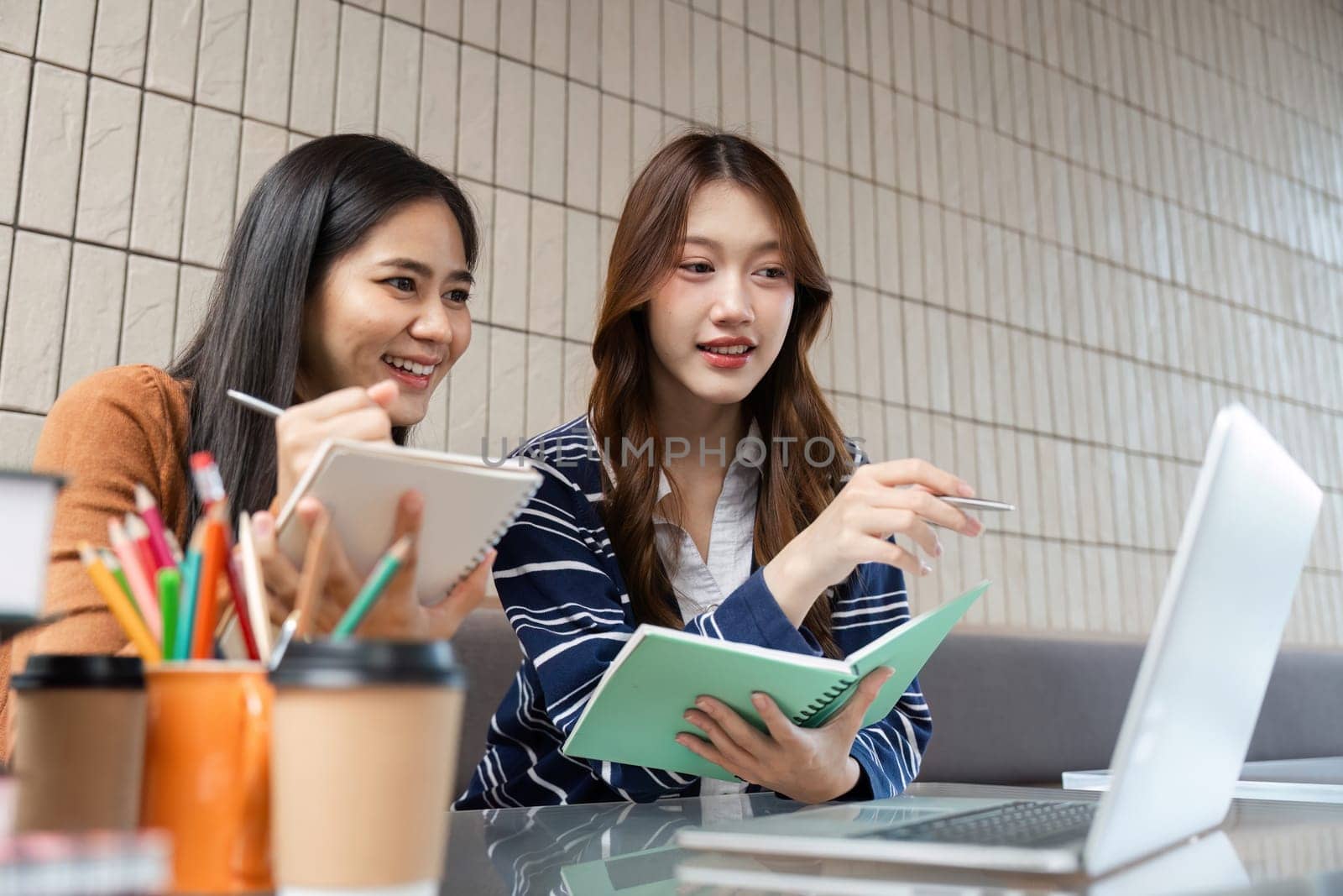 Two students share insights while studying together at a cafe. They enjoy discussing concepts while reviewing their notes and digital resources.