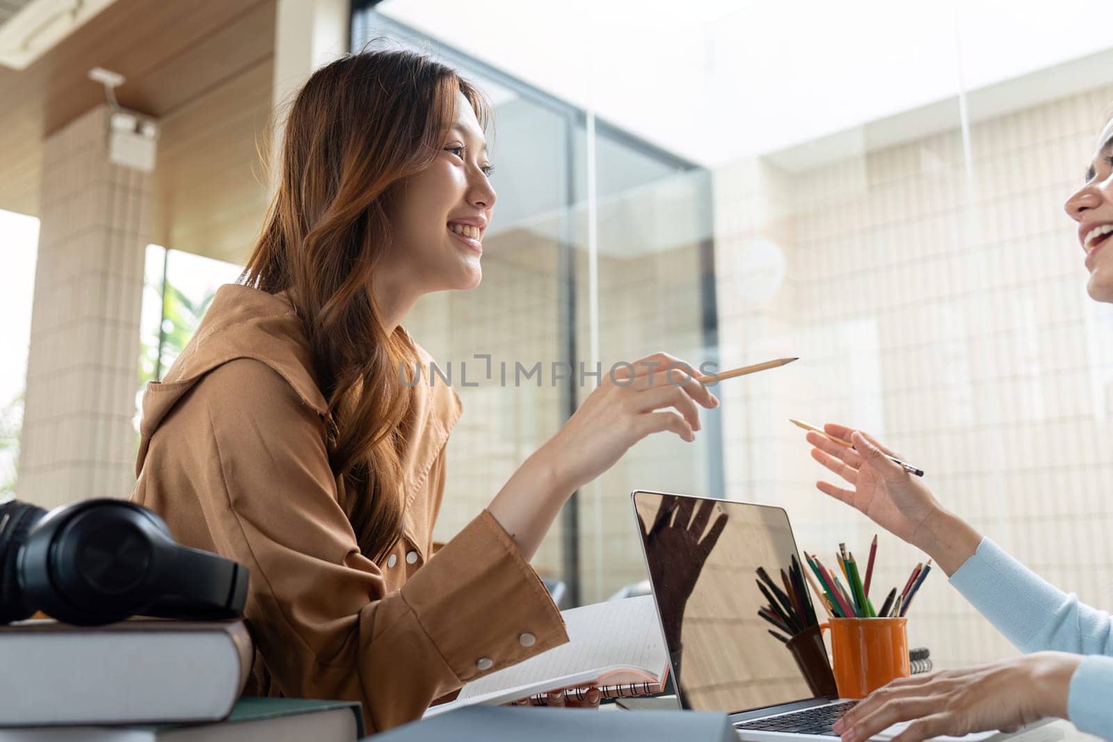 Two students are sharing a joyful conversation while studying, emphasizing the importance of connection and support in education.