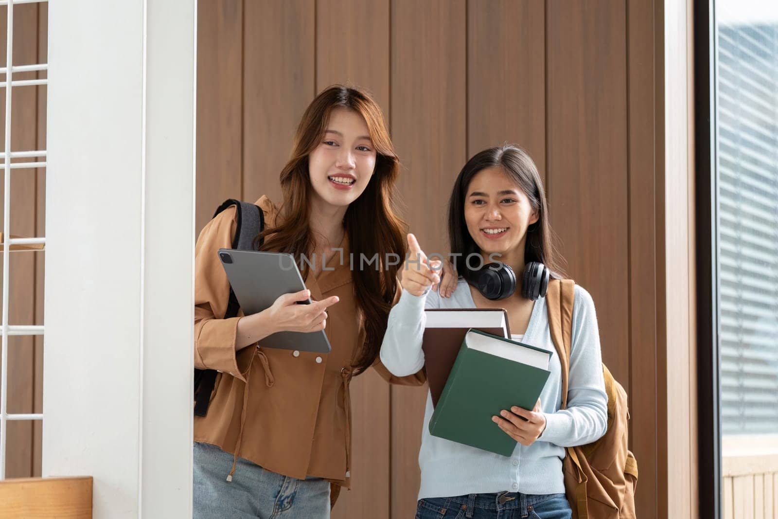 After a successful study session, two friends pose happily, showcasing their academic tools as symbols of achievement and teamwork.