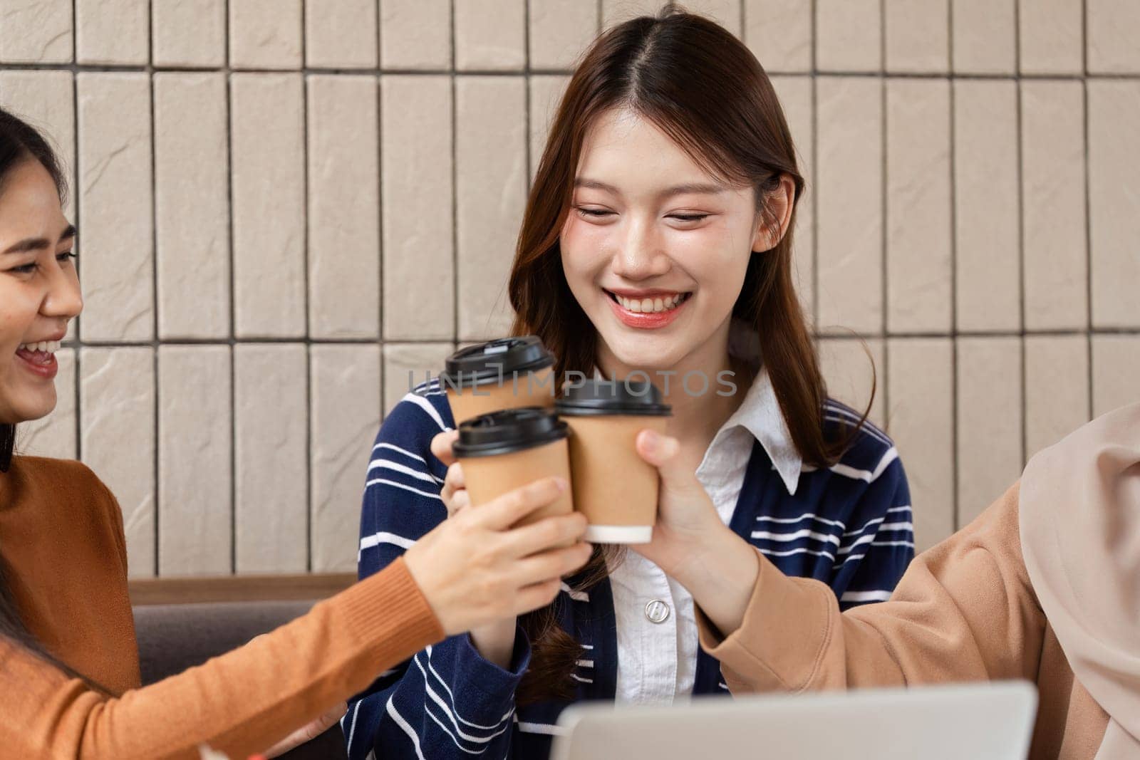 The three friends raise their coffee cups in celebration, capturing a moment of unity and joy as they share a special occasion together.