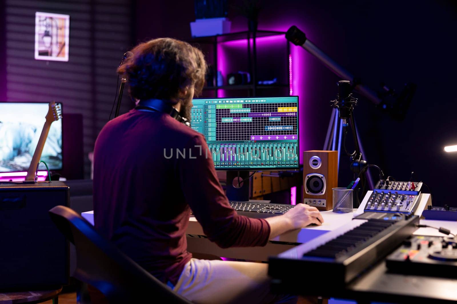 Sound engineer working in his home studio with daw software on computer and mixing tools, creating music. Producer mixing and mastering soundtracks, signal processing acoustical engineering.