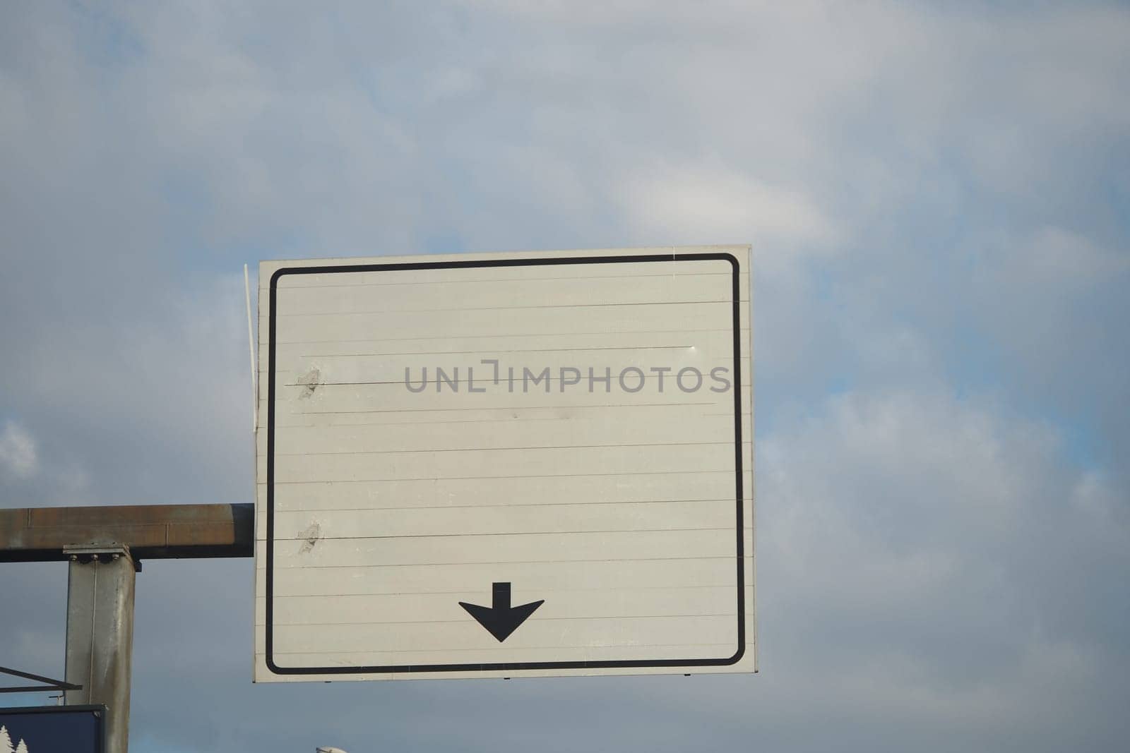 Blank traffic sign with downward arrow against a cloudy background.