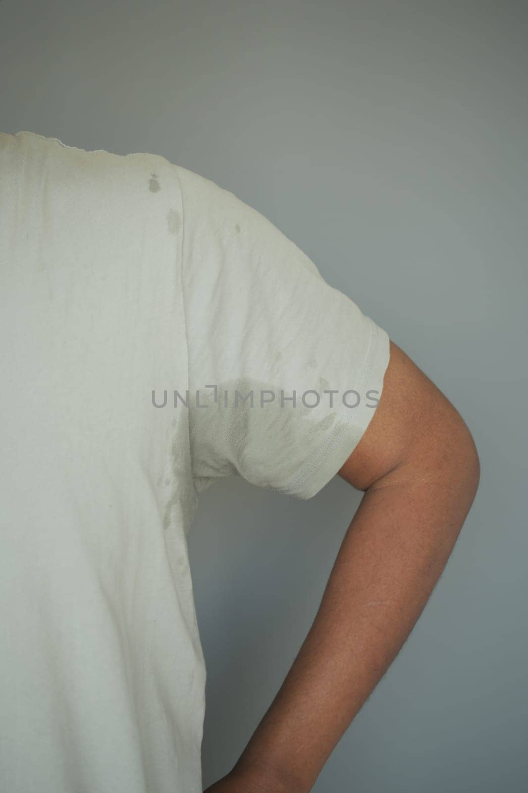 A person stands with one arm resting at their side, showing sweat marks.