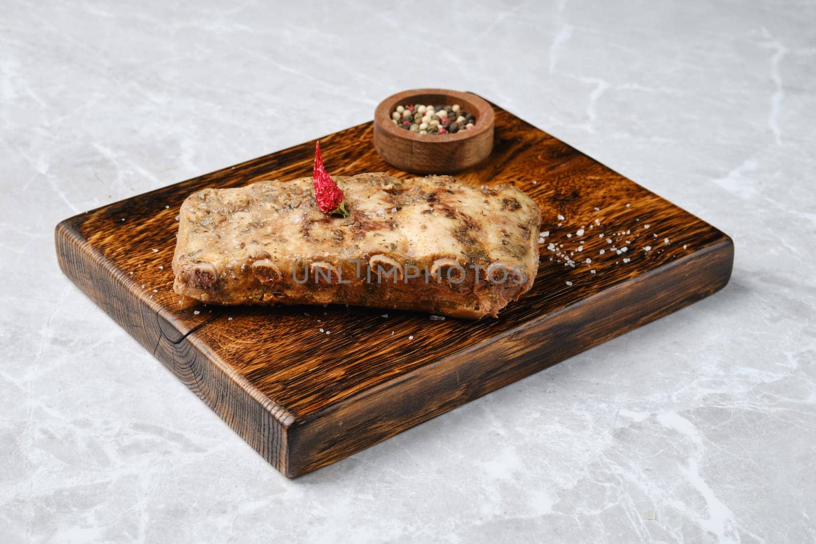 Roasted spicy pork ribs on a rustic wooden board, with a small bowl of mixed spices