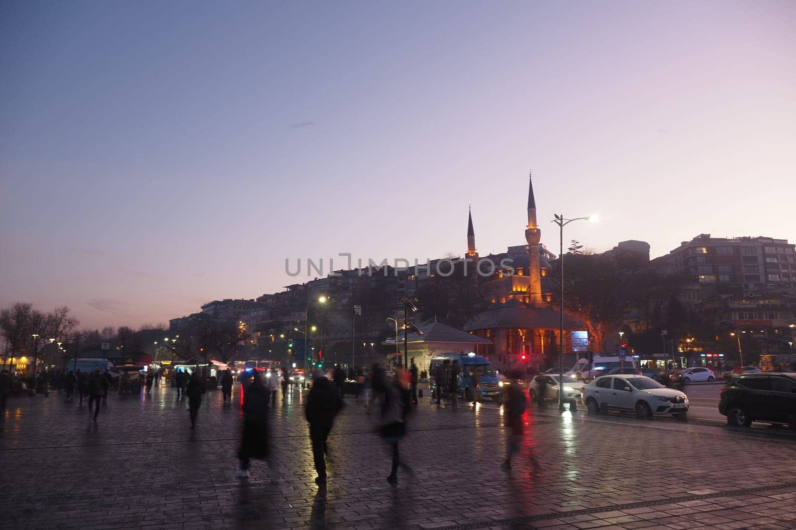turkey istanbul 23 june 2024. People stroll through a bustling city square at dusk near a mosque.