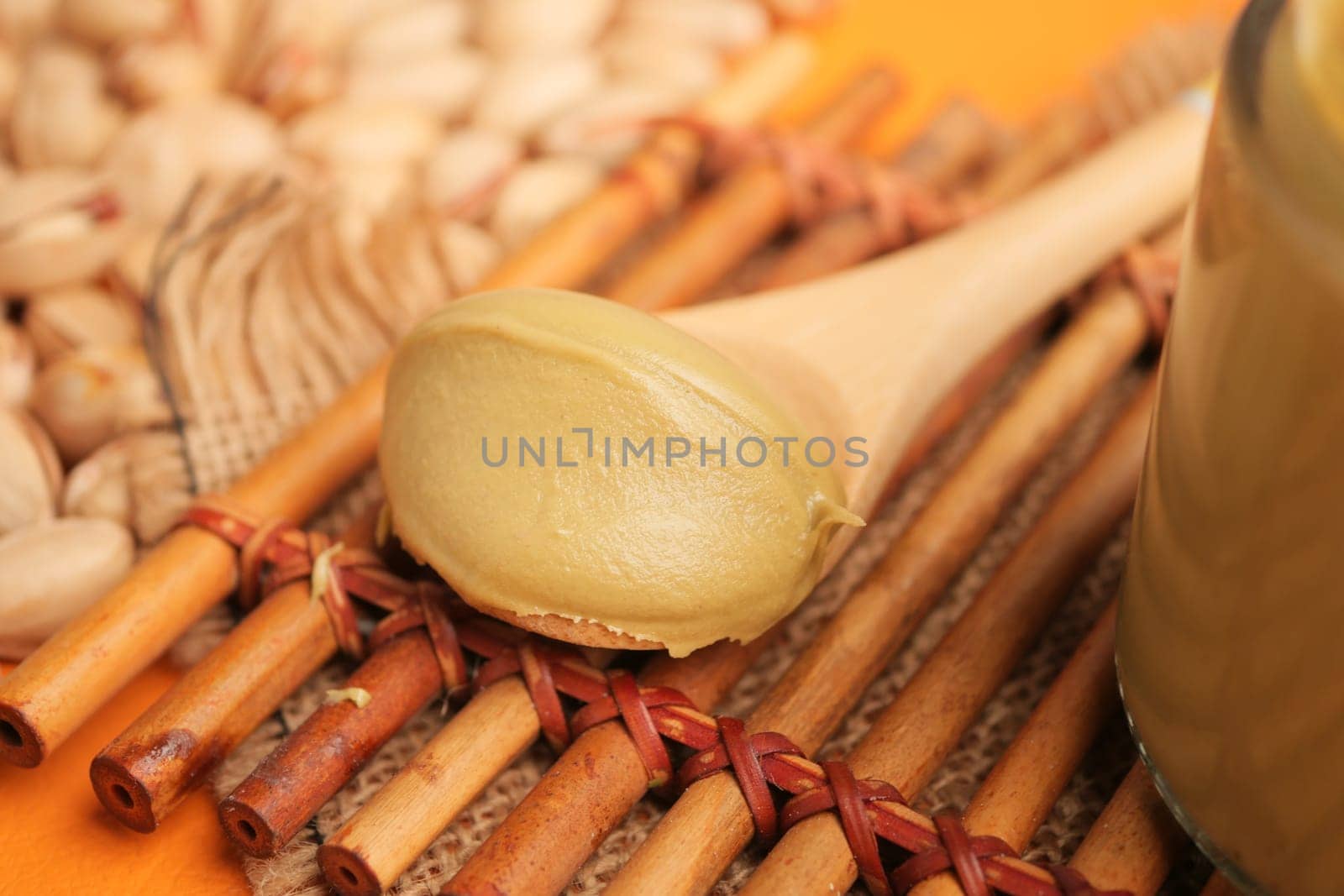 Creamy pistachio butter rests on a spoon amid scattered nuts and textures.