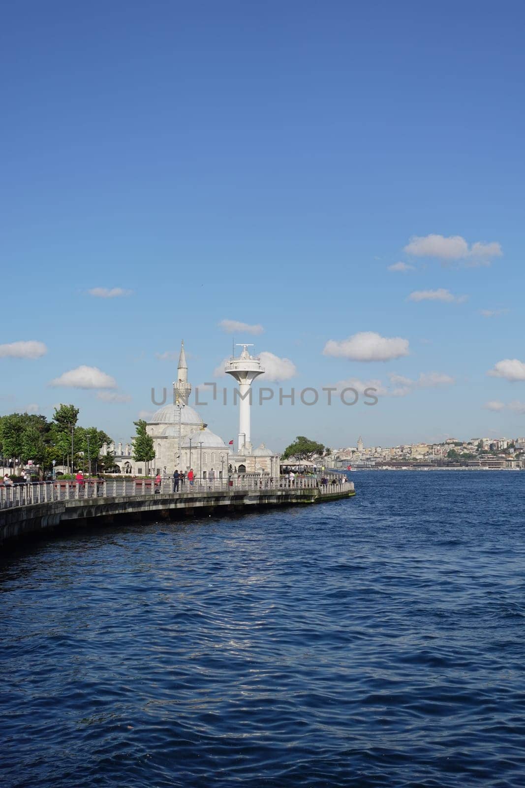People stroll along the water's edge, enjoying the beautiful day in Istanbul.