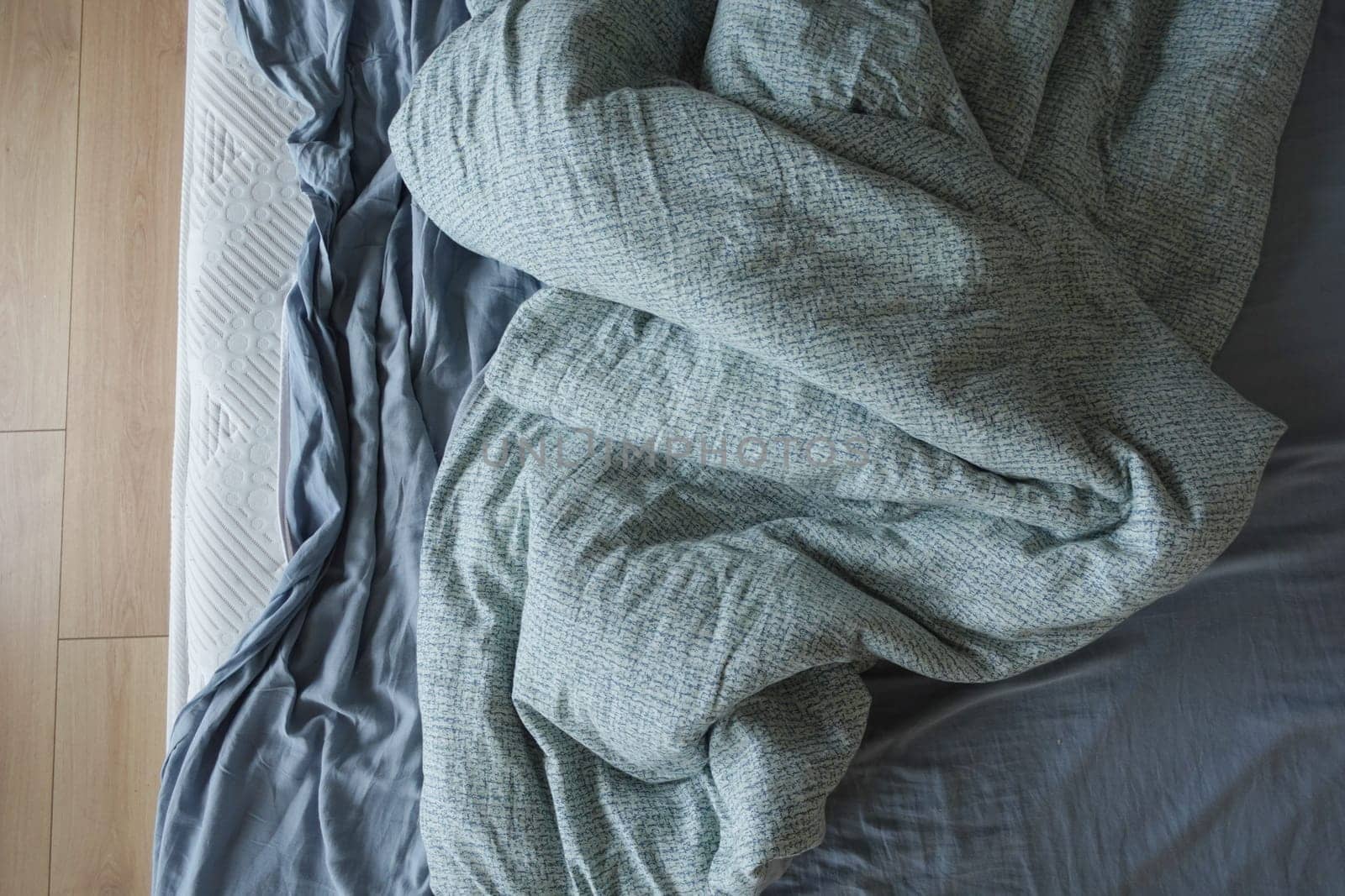 messy bedroom setting with a rumpled blanket on a bed.