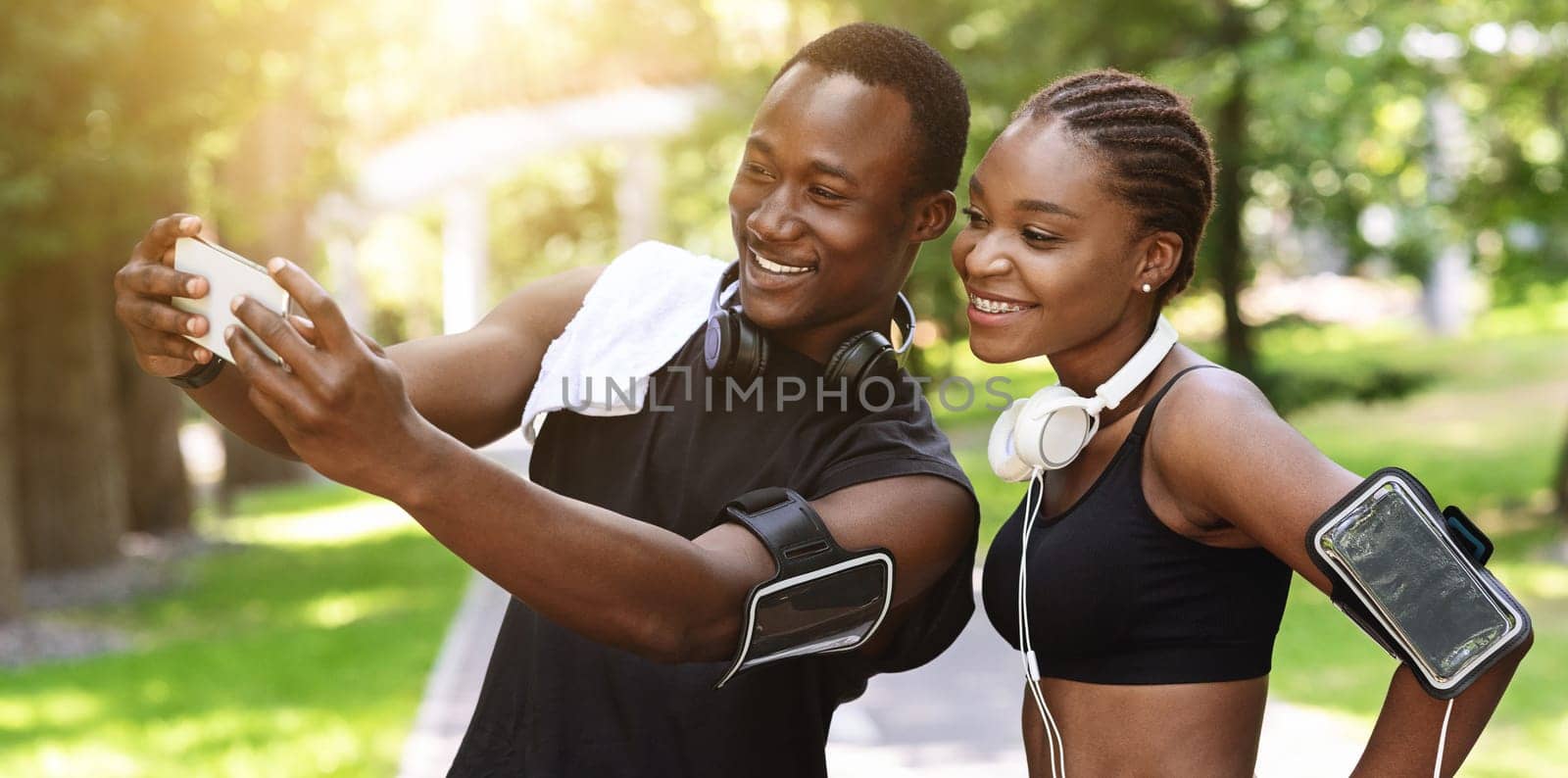 Black Millennial Couple Taking Selfie On Smartphone While Doing Sport Together Outdoors, Looking At Device Camera And Smiling