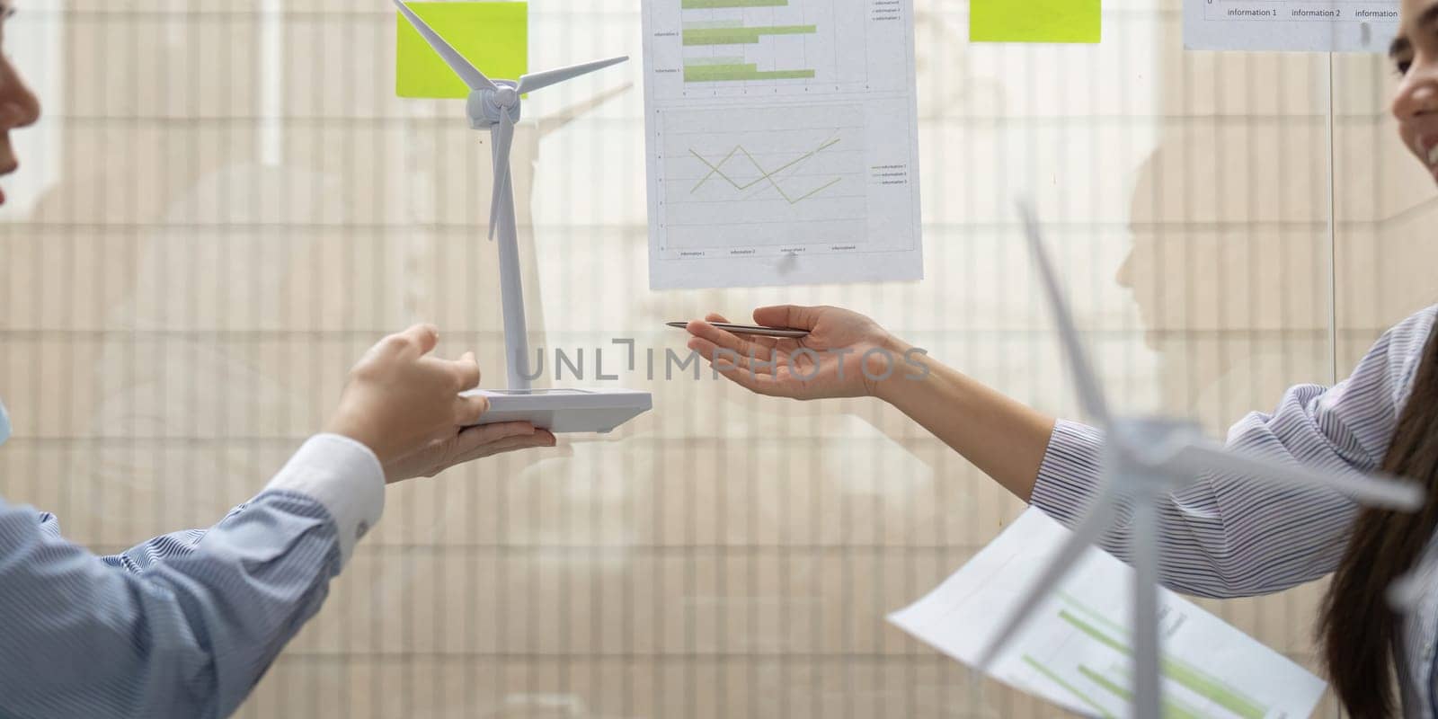 Two corporate professionals collaborate on renewable energy initiatives, exchanging models, and insights on sustainability metrics related to wind energy solutions.