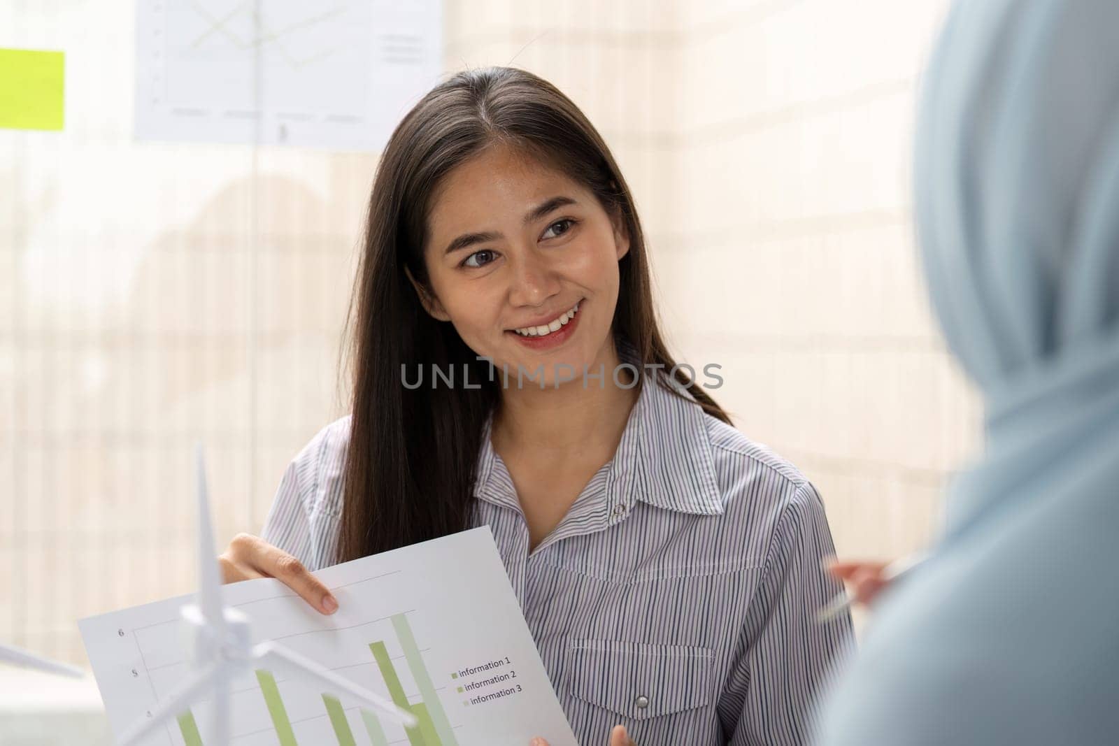 A young woman passionately explains sustainability metrics and ESG strategies, showcasing her expertise in a collaborative work environment.