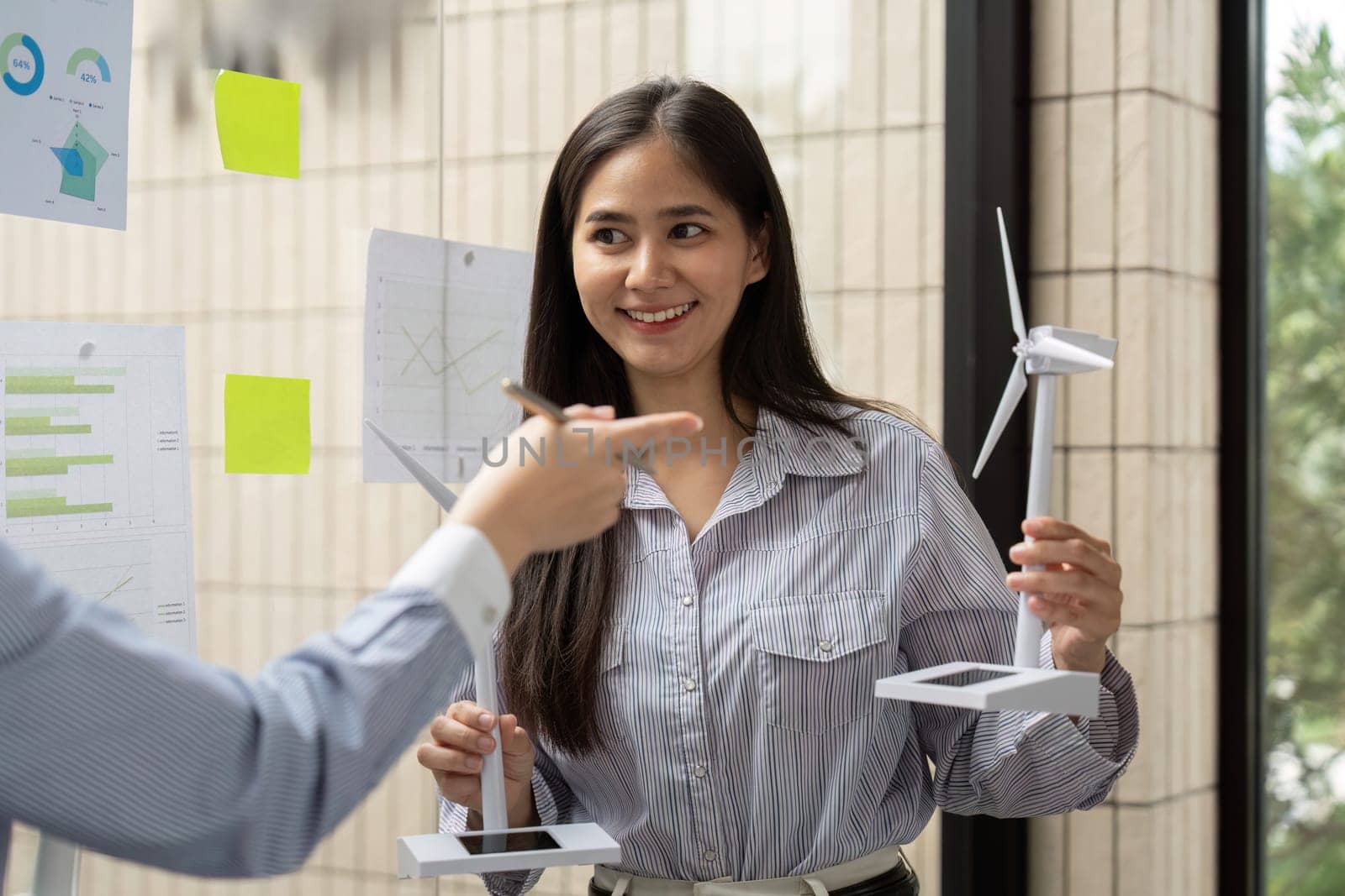Two professionals exchange ideas on renewable energy while reviewing models, demonstrating collaboration on innovative sustainable solutions in a workspace designed for creativity.