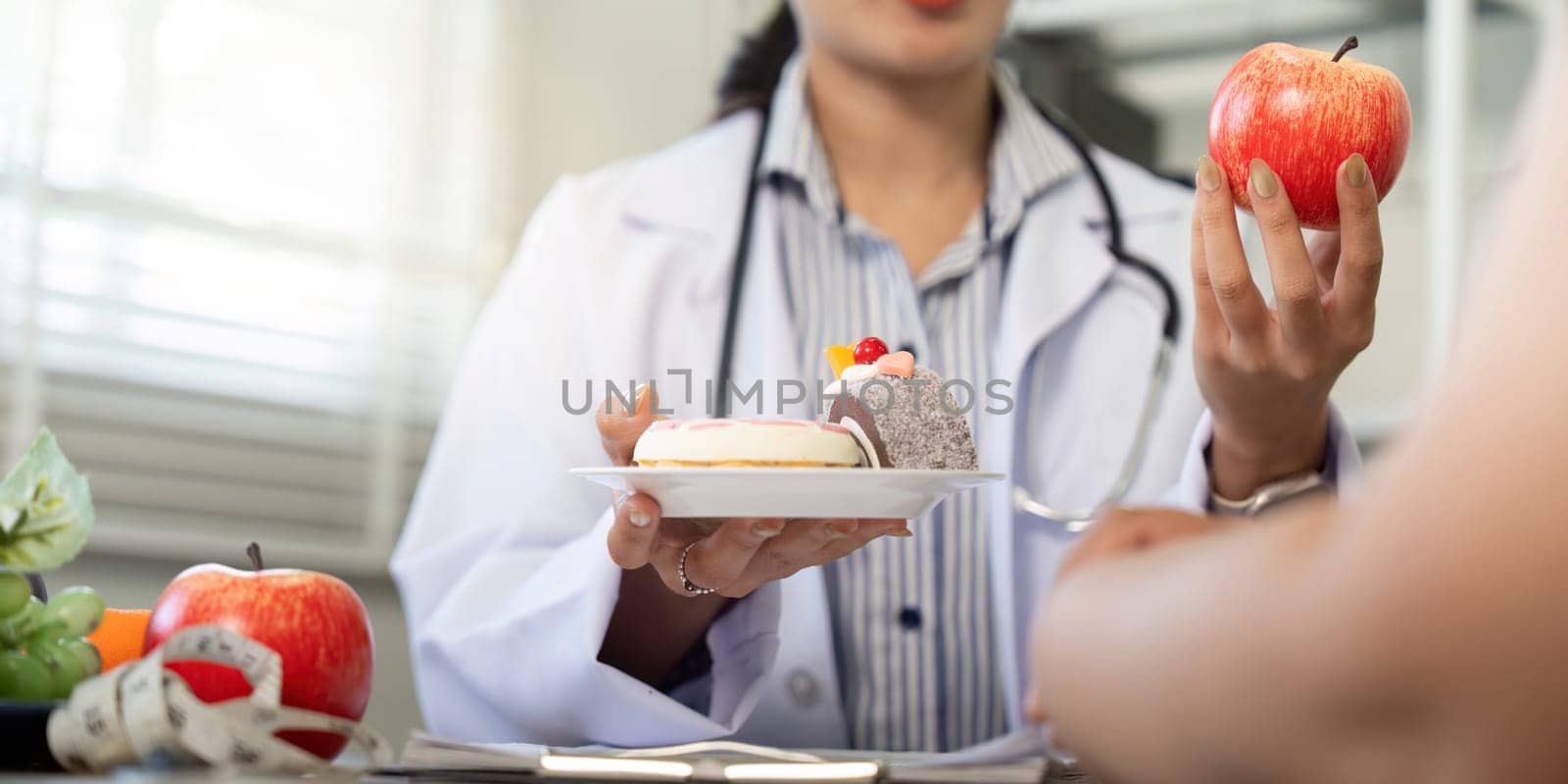 During a consultation, the healthcare professional encourages the patient to consider healthy food options like fruits while presenting a dessert.