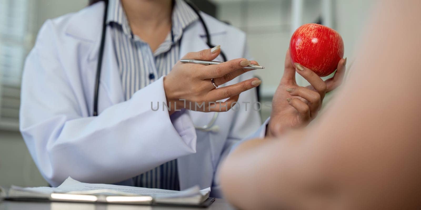 A doctor emphasizes the importance of balance in dietary choices by presenting both a dessert and a healthy apple to the patient.