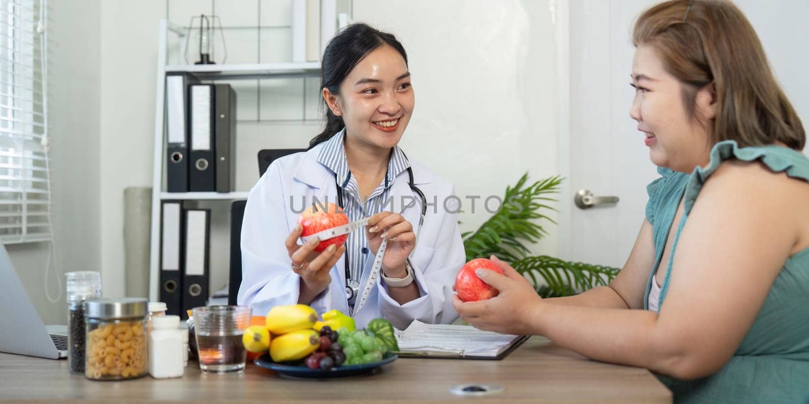 In a supportive consultation, a nutritionist holds apples while explaining their health benefits, engaging her patient in a friendly discussion about nutritious choices.