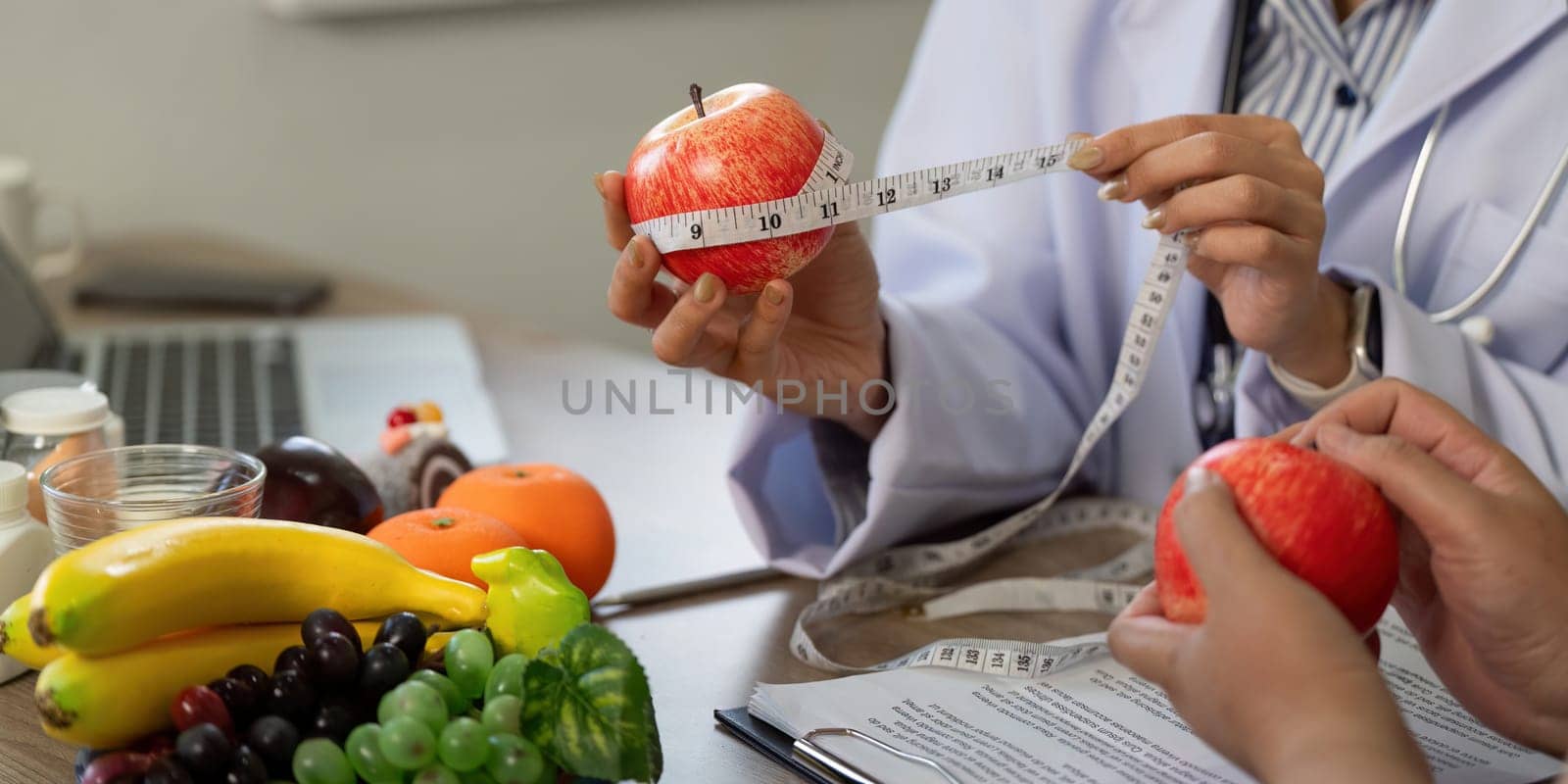 During a nutrition discussion, a medical professional measures apples to illustrate portion sizes while discussing healthy eating habits with a patient.