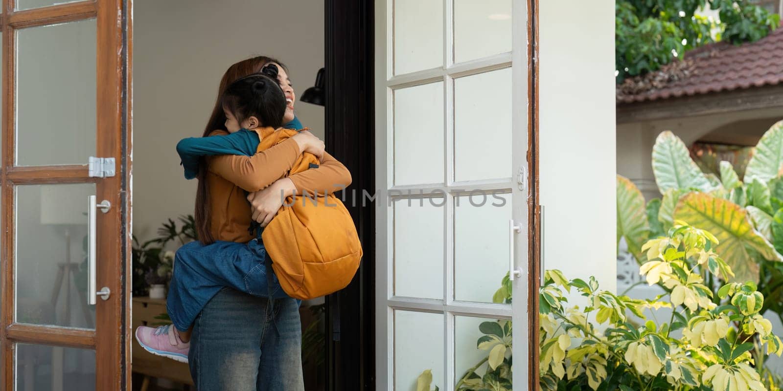 A joyful scene where a mother lifts her daughter in a warm embrace at the door after school, illustrating the cherished family moments filled with love and happiness.