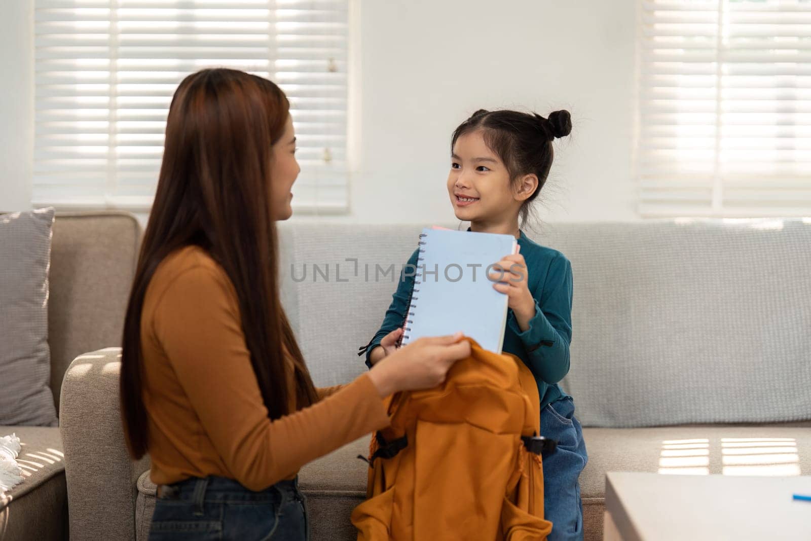 A young girl presents her notebook to her mother, showcasing her excitement for school. This moment reflects the joy of learning and parental support.