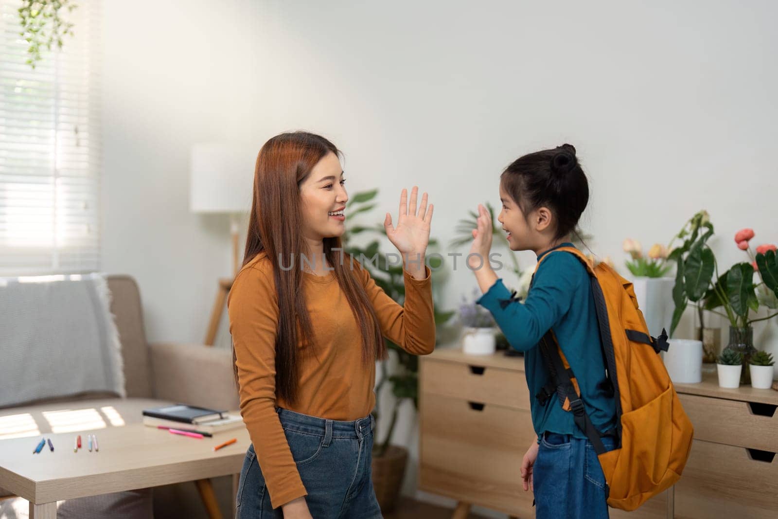 The mother and daughter share a joyful high-five, expressing their excitement for the day ahead. This moment represents support and togetherness.