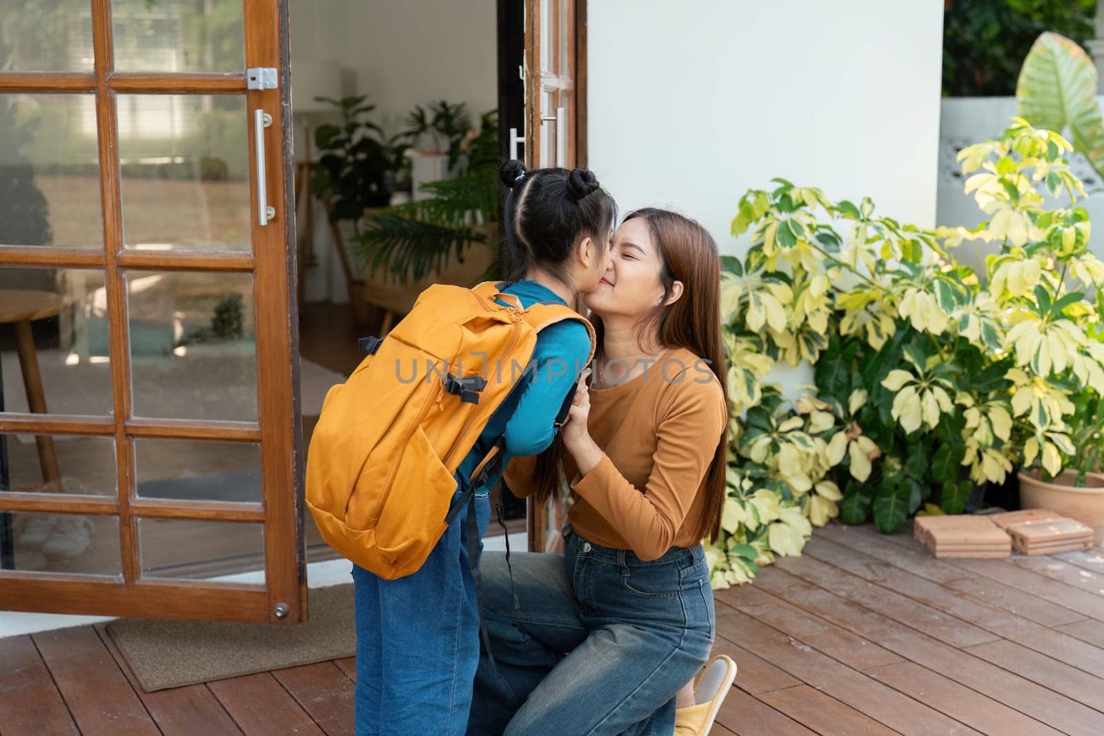 A mother and her daughter embrace in a warm farewell at home, highlighting the emotional connection of family as the child heads off for school. This moment captures love and support.