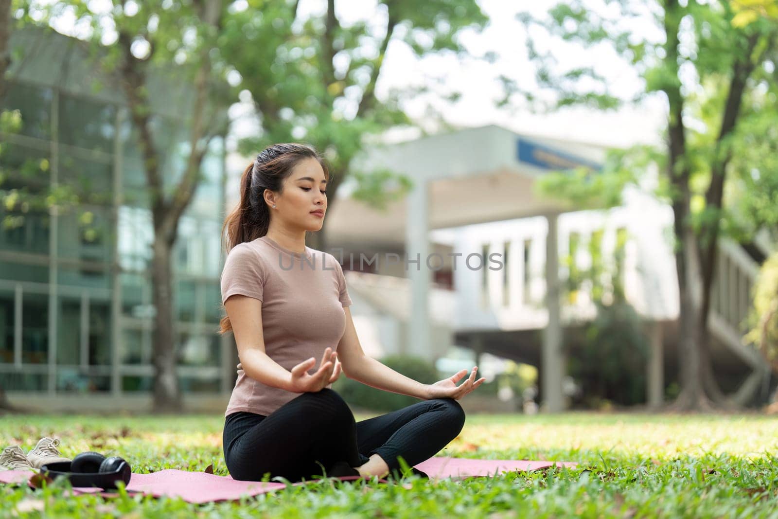Seated in a calm outdoor setting, a woman meditates with her eyes closed, embracing mindfulness as part of her daily wellness routine.