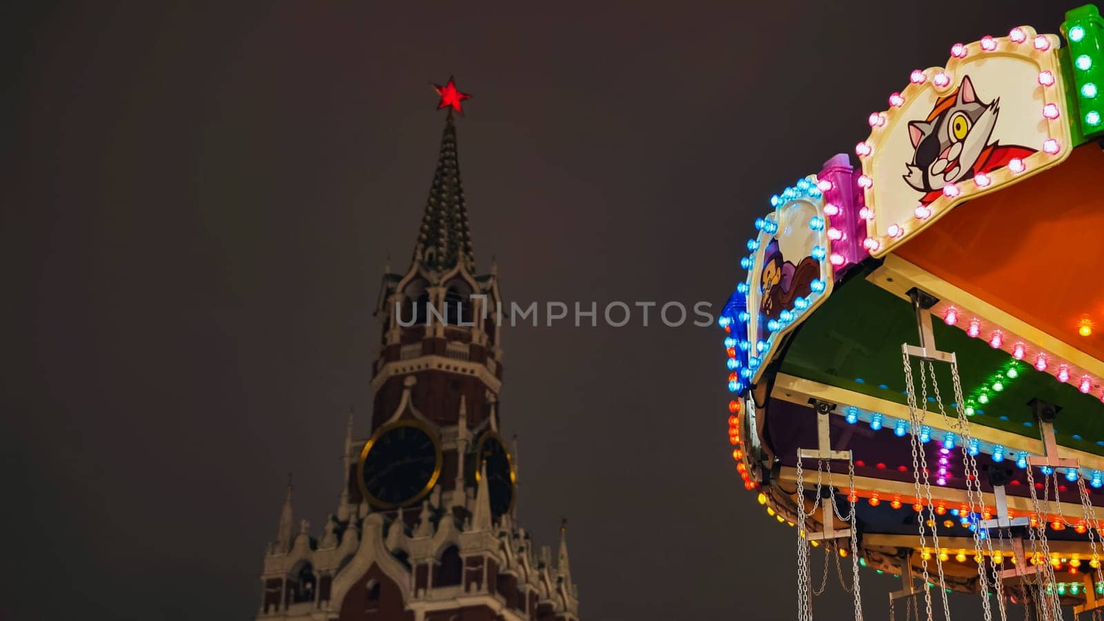 Brightly lit carousel with Spasskaya Tower in the background during Moscow Christmas festival