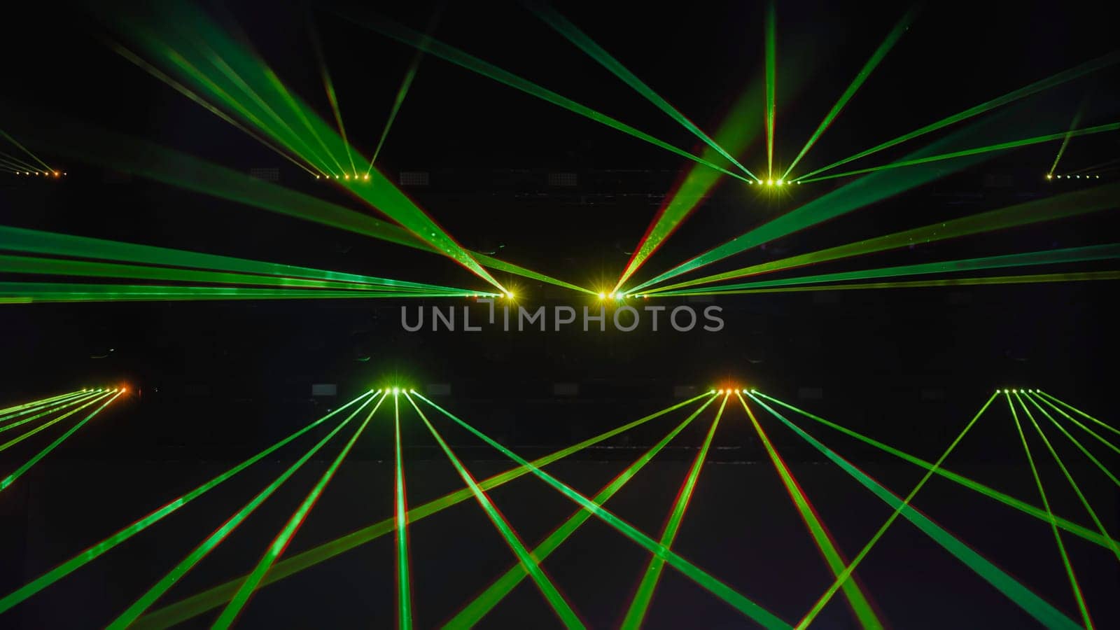 Green laser beams crossing each other during a music show in a dark concert hall