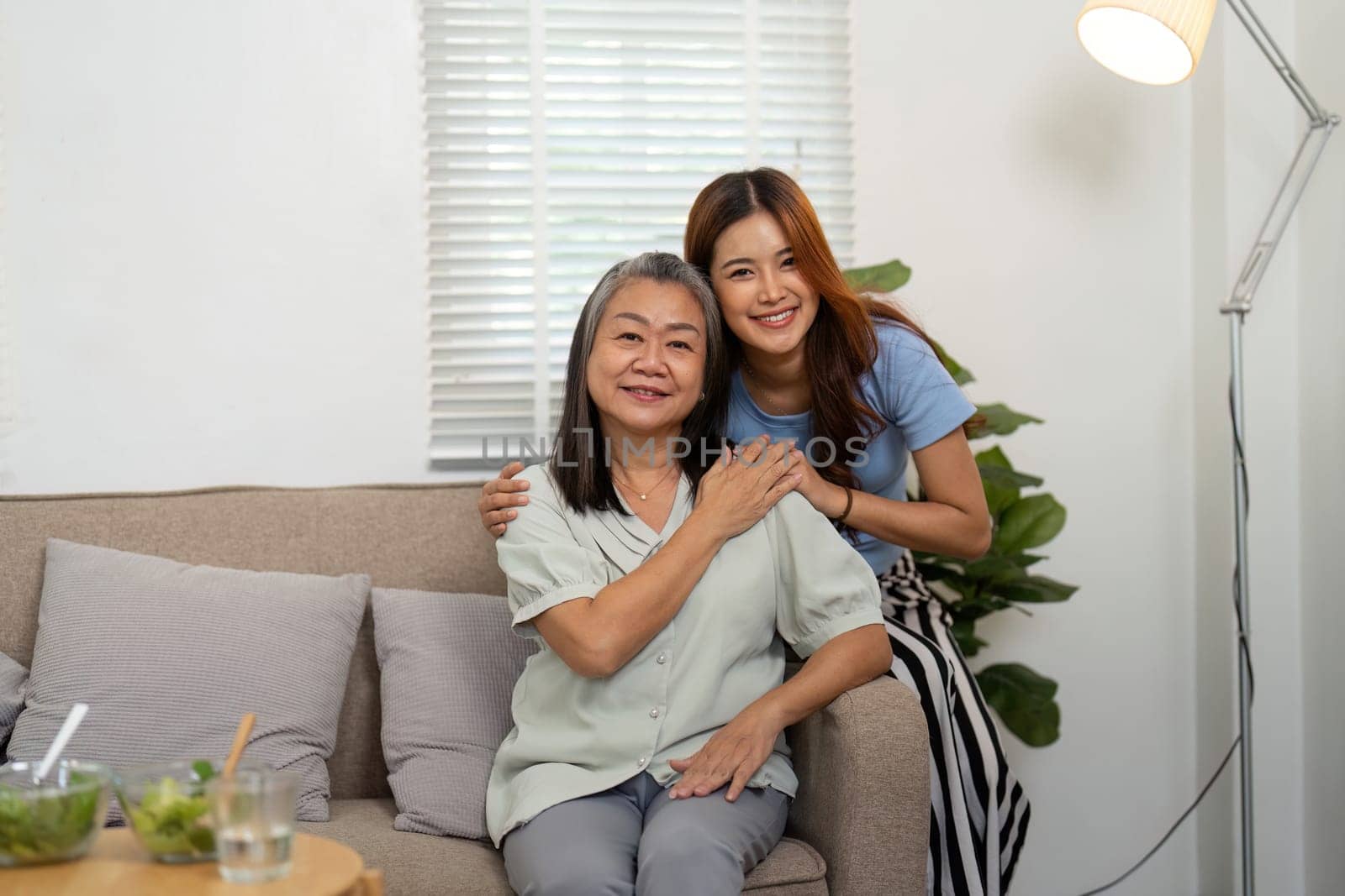 In a warm living room, a mother and daughter share a heartfelt embrace, highlighting their emotional bond and familial love.