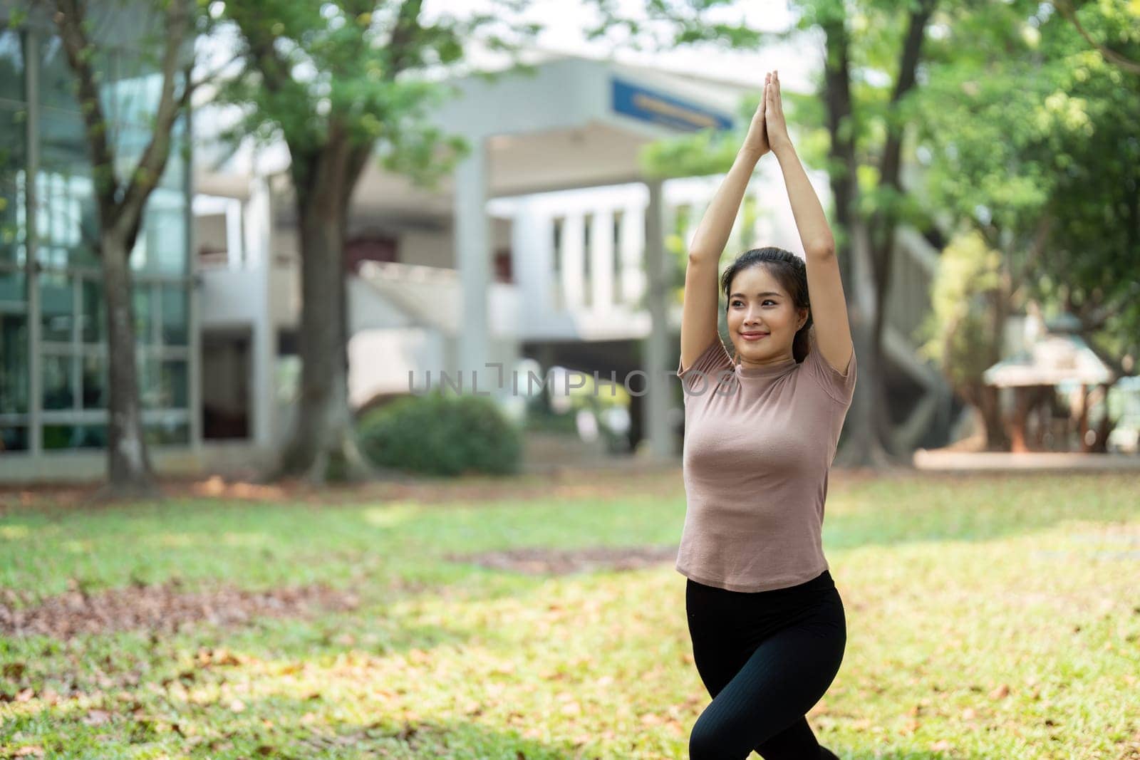 Focusing on her breath, a young woman performs yoga in a serene environment, incorporating nature into her exercise routine for holistic wellness.