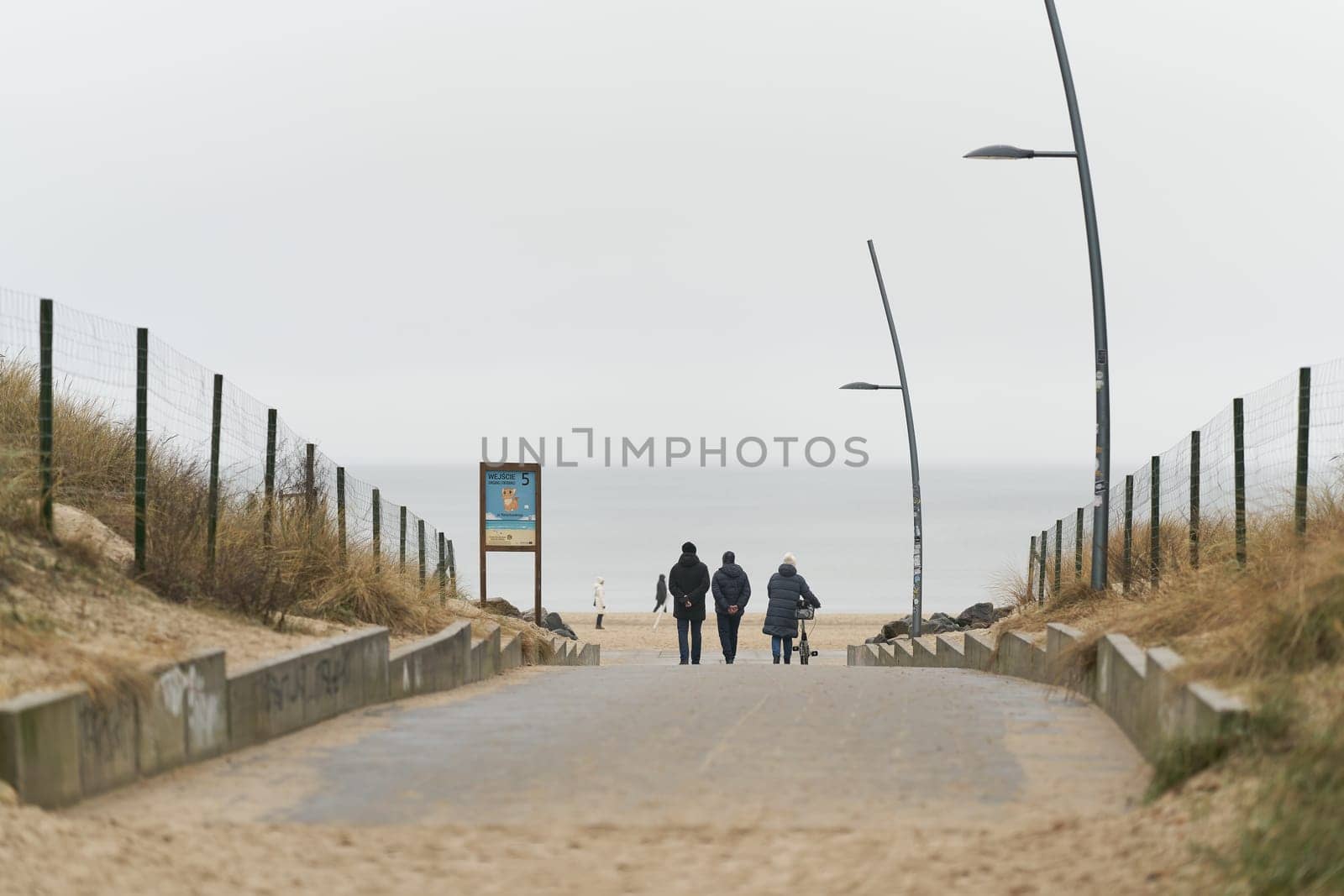 Swinoujscie, Poland – December 26, 2024: Vacationers on a path to the beach of Swinoujscie, Swinemunde on the Polish Baltic Sea coast out of season in winter