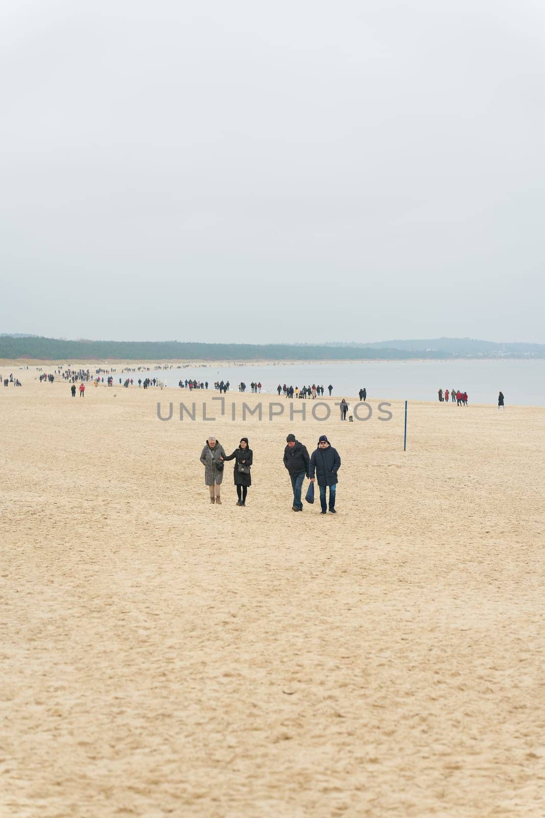 Swinoujscie, Poland – December 25, 2024: Vacationers during a walk on the beach of Swinoujscie, Swinemunde on the Polish Baltic Sea coast in winter