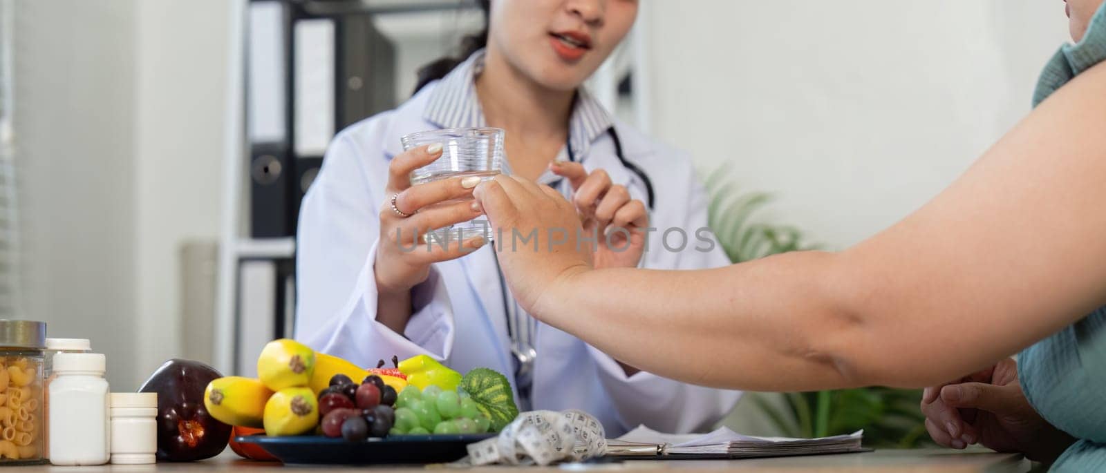 A healthcare professional engages with a patient, showcasing a variety of fresh fruits and emphasizing hydration with a glass of water. The session highlights the importance of nutrition and wellness.
