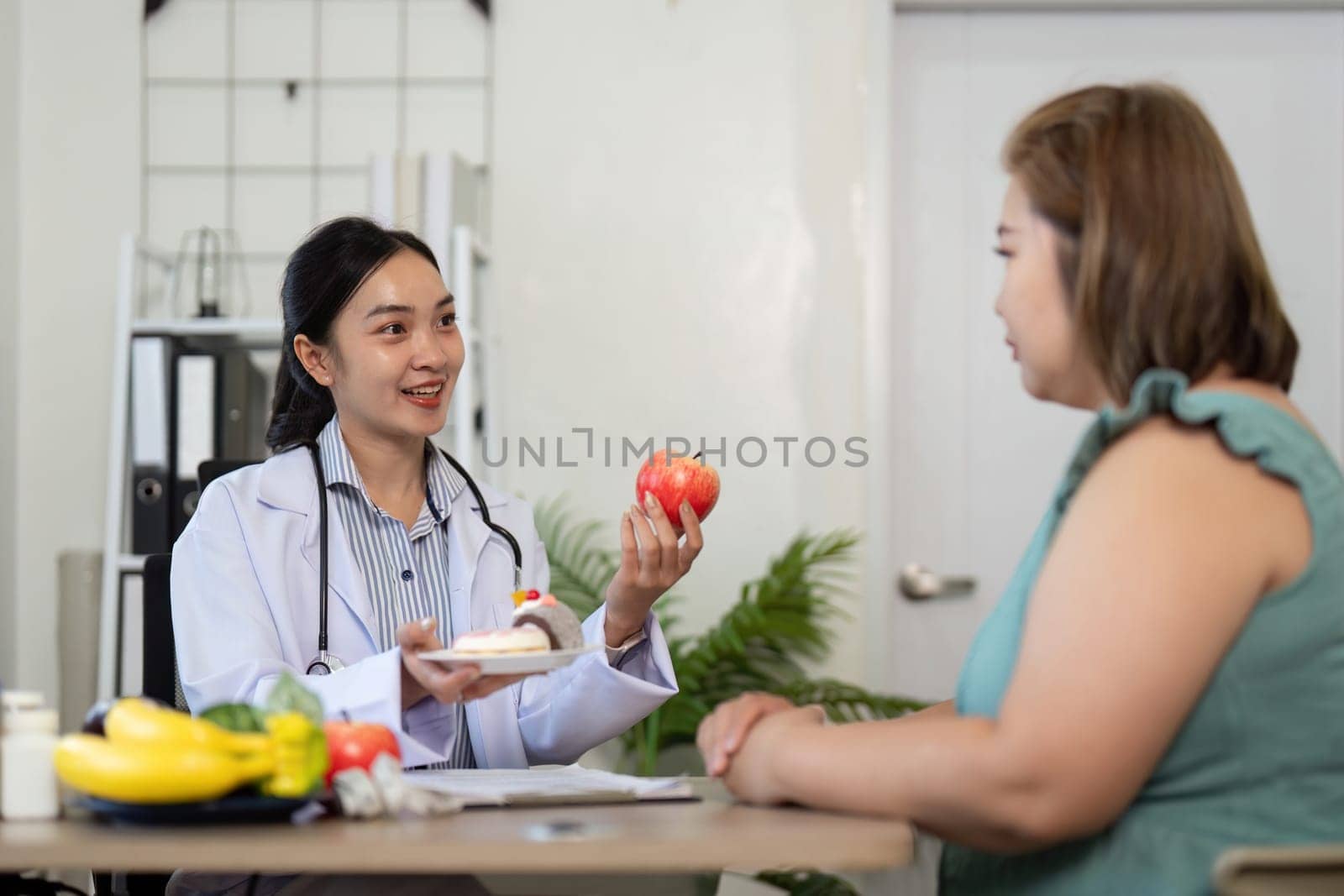A nutritionist excitedly presents an apple to her client while discussing balanced meal options, highlighting the importance of dietary choices in a wellness plan.