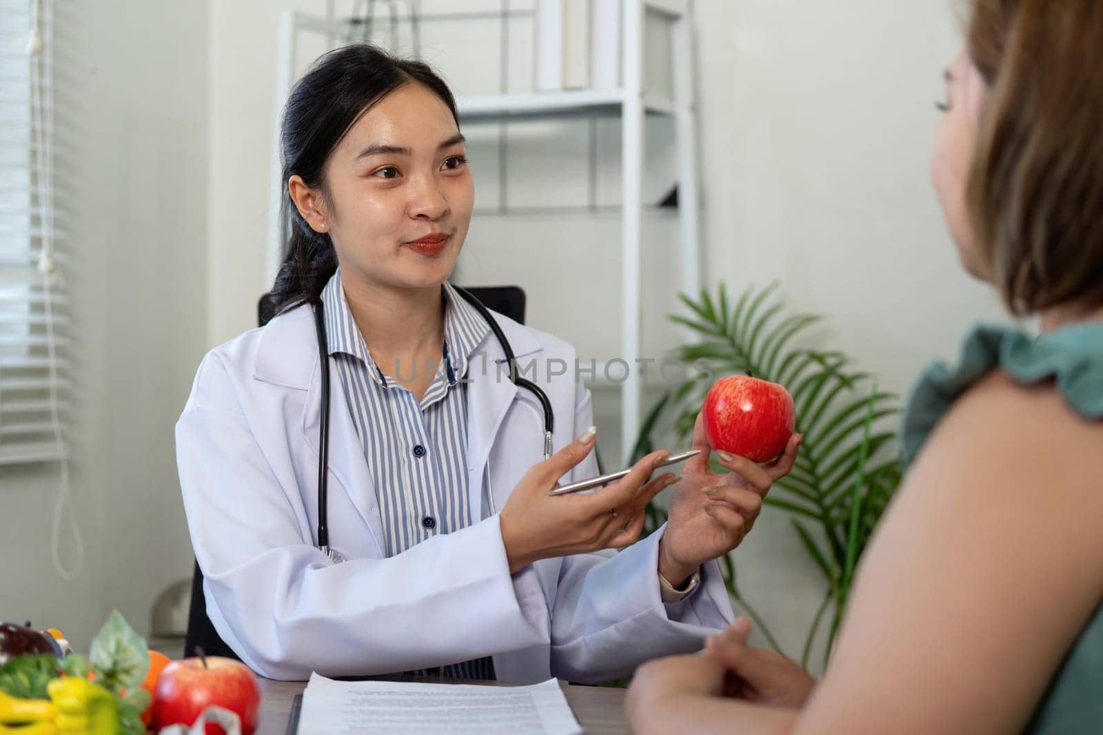In a friendly consultation, a healthcare professional discusses the nutritional benefits of apples to encourage healthier habits in her patient.