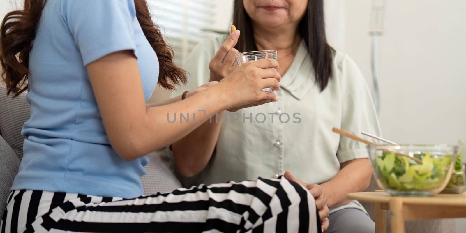 In a cozy living room setting, a mother and daughter share a moment of health as they enjoy nutritious drinks, emphasizing family care and wellness routines.