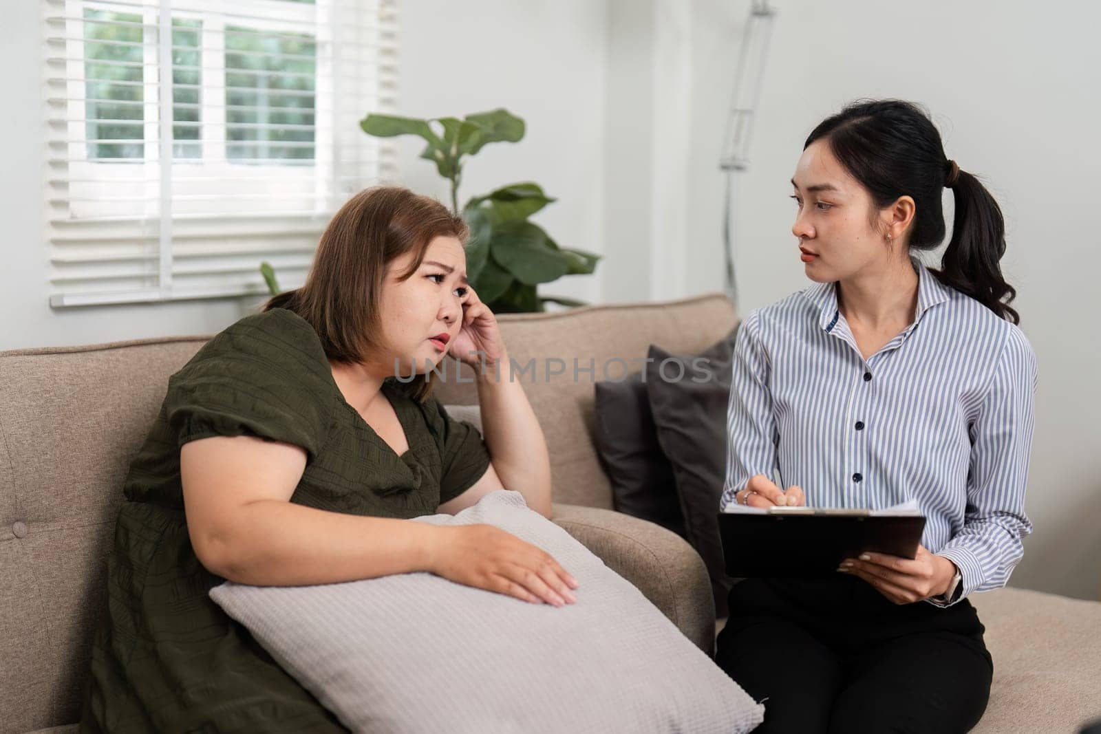 In a comfortable setting, a psychiatrist assists a client in expressing her feelings. The therapist offers compassionate support, enhancing the therapeutic experience and fostering emotional healing.