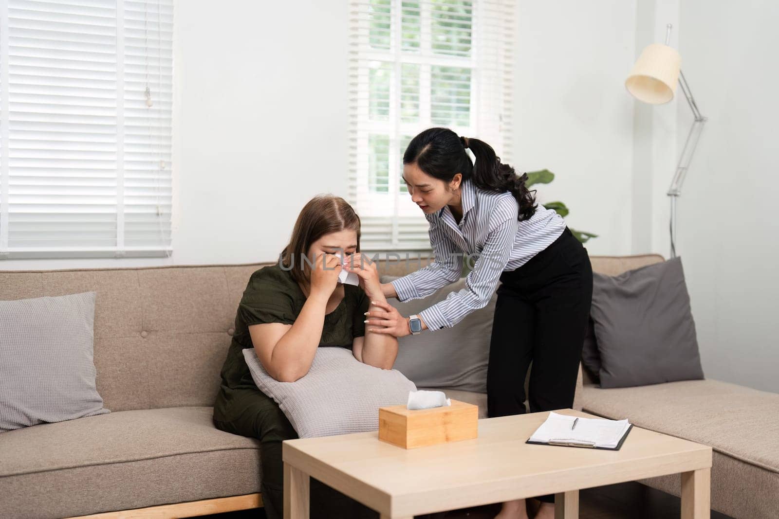 In a cozy therapy room, a psychiatrist reaches out to comfort a distraught patient, fostering a nurturing environment for emotional healing and connection.