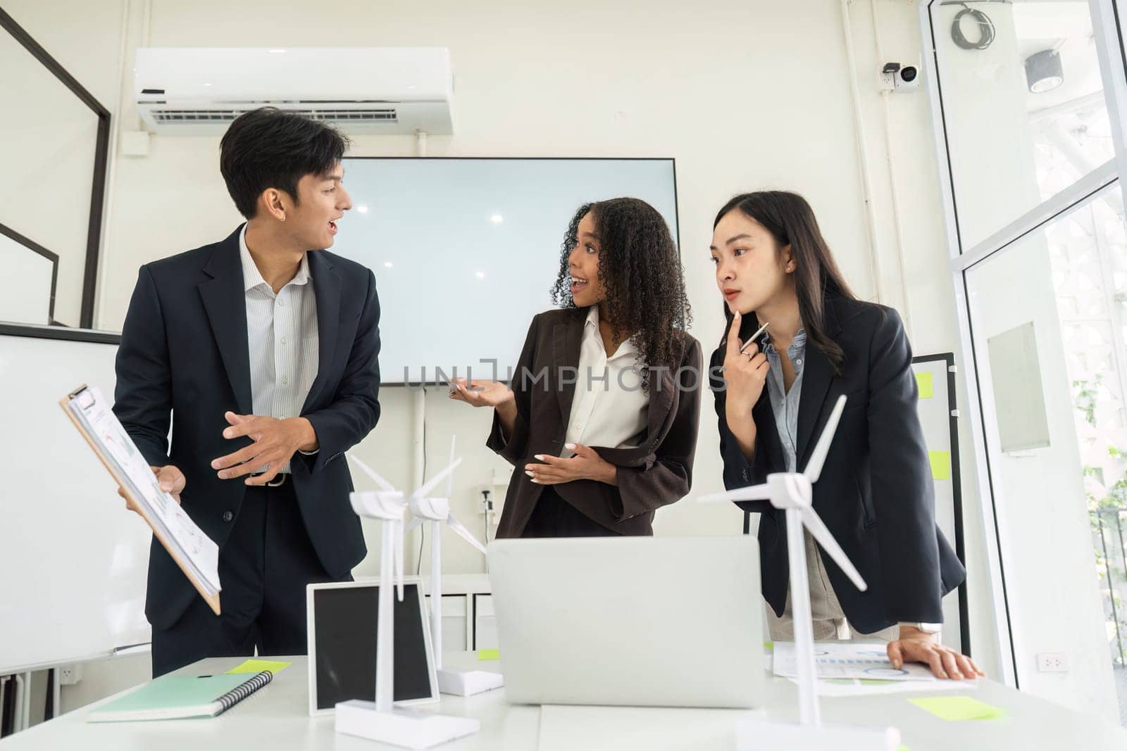 Three professionals engage in a dynamic discussion about sustainable practices and ESG strategies in a contemporary office environment.