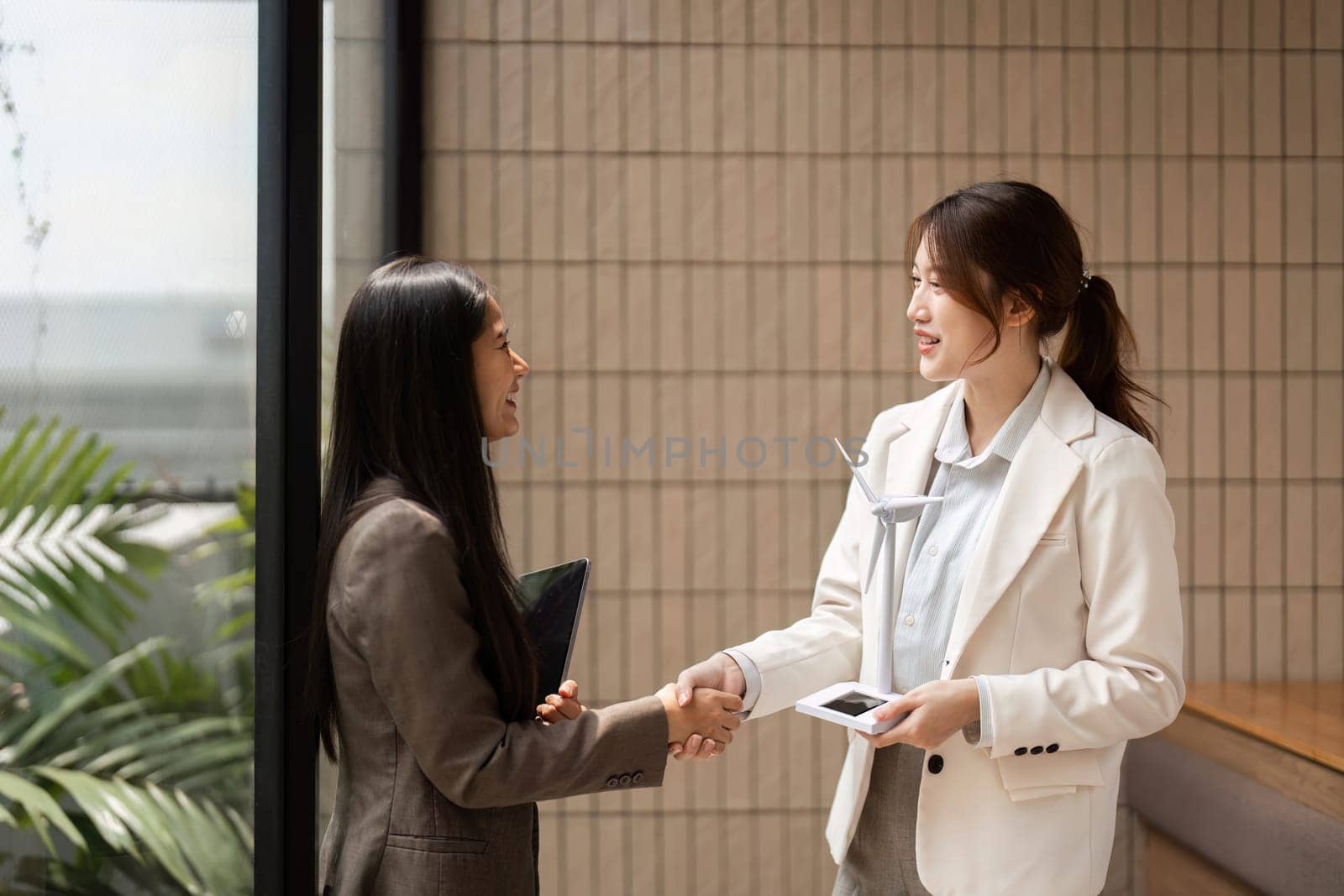 Two professionals solidify their partnership by engaging in a handshake, representing their shared commitment to sustainability and innovation within their business strategy.
