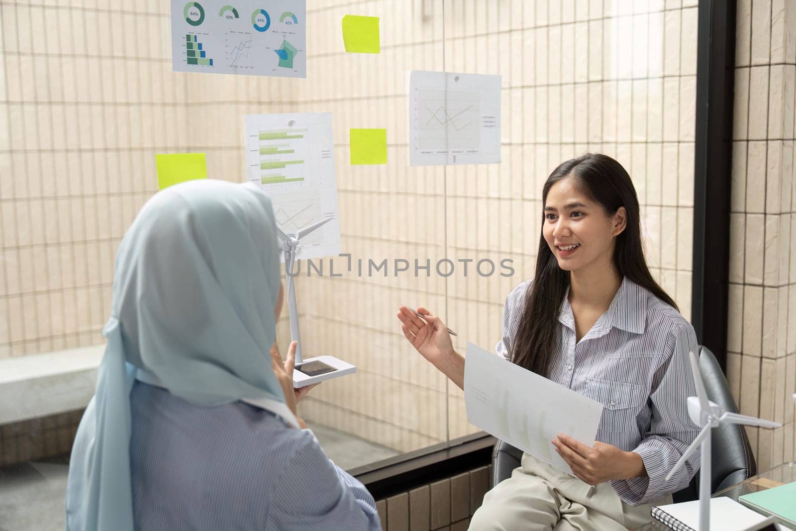 In a professional environment, two women engage in an insightful conversation on ESG frameworks, focusing on creating sustainable business practices that drive positive change.