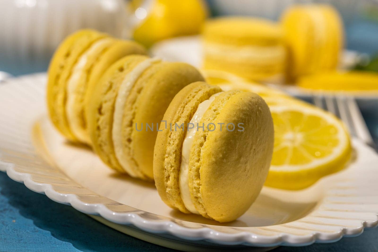 Delightful yellow lemon macarons, filled with creamy white goodness, beautifully arranged on a white plate alongside fresh lemon slices