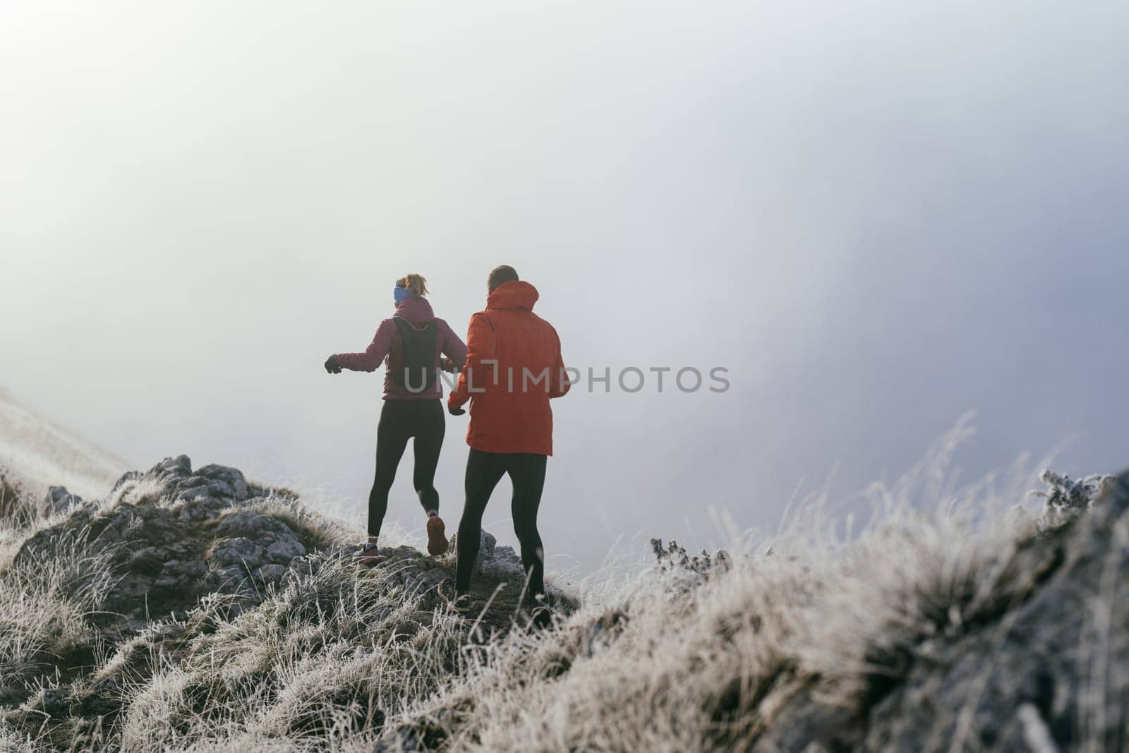 Trail running couple man and woman running on a mountain path. A couple on cross country run in early morning.
