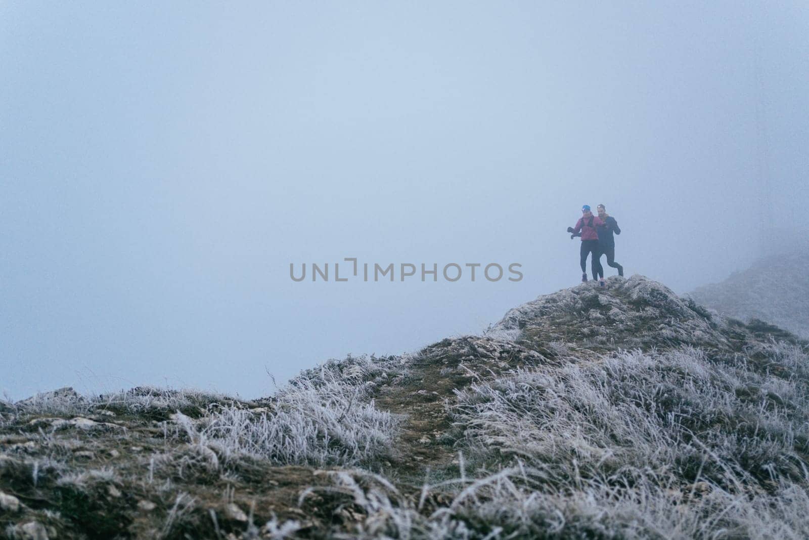Trail running couple man and woman running on a mountain path. A couple on cross country run in early morning.